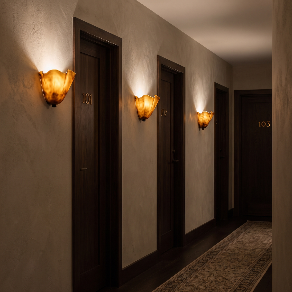 Three Kira artistic wall sconces in brown glass lit along a boutique hotel corridor