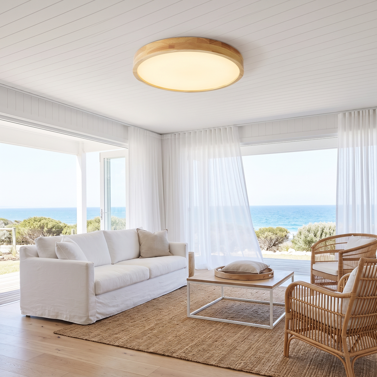 Lerie round timber LED ceiling light in a coastal living room with a white slipcovered sofa