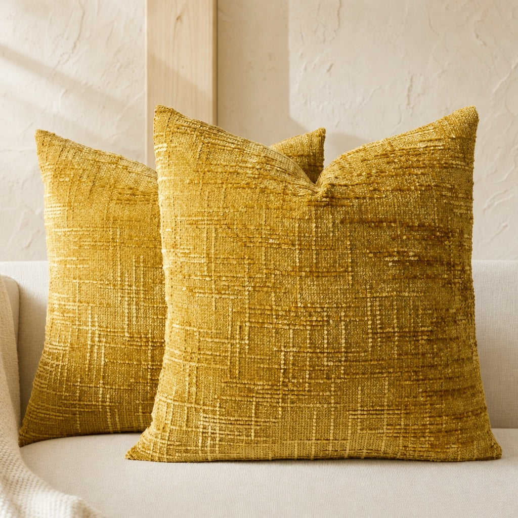 Pair of Lucina chenille throw pillows in yellow on a cream sofa in warm window light