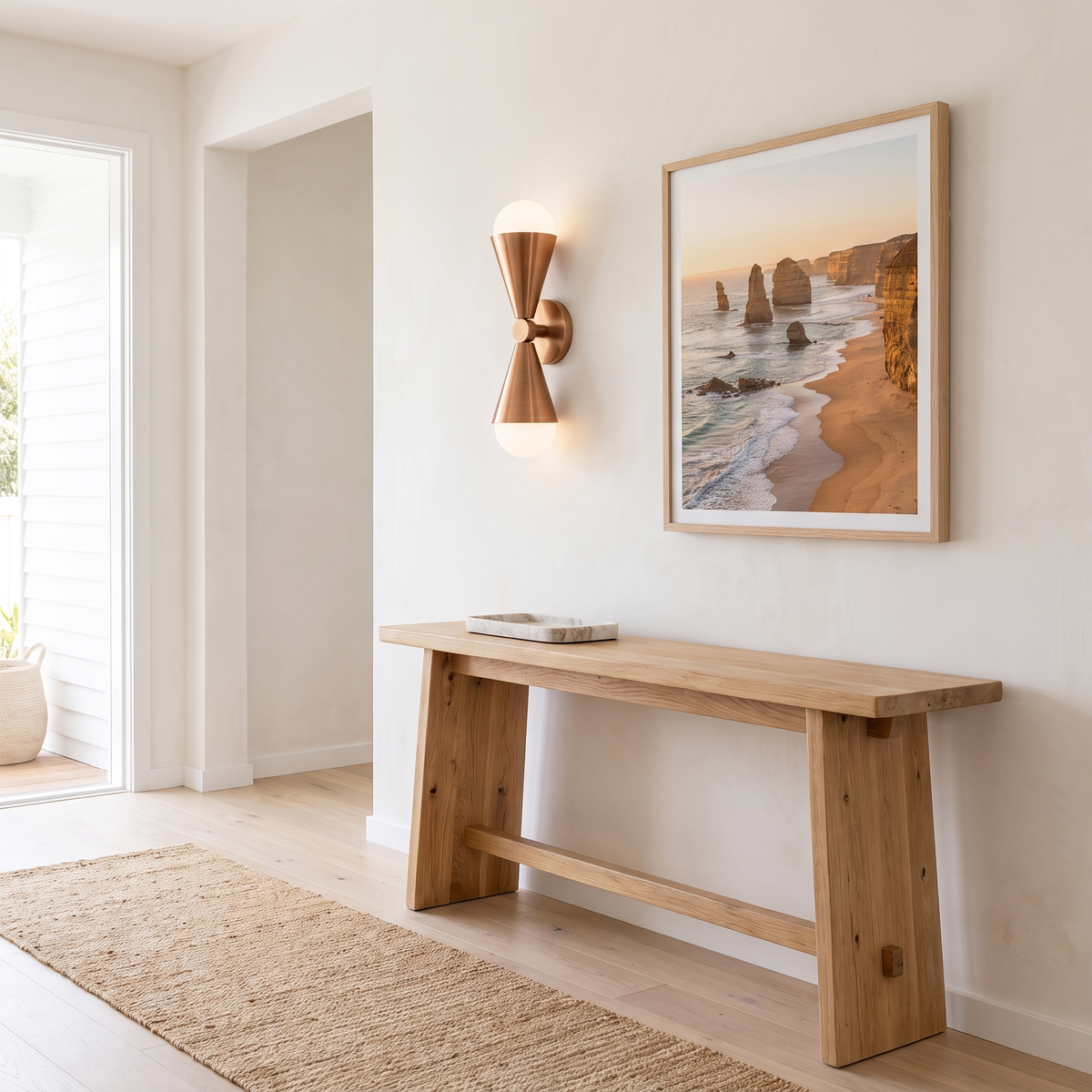 Lura copper hourglass wall sconce above an oak console in a coastal entry hall