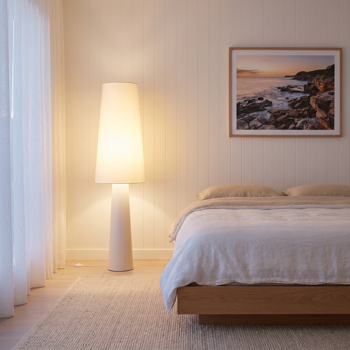Marit Modern Floor Lamp lit in a coastal bedroom corner beside a low oak platform bed