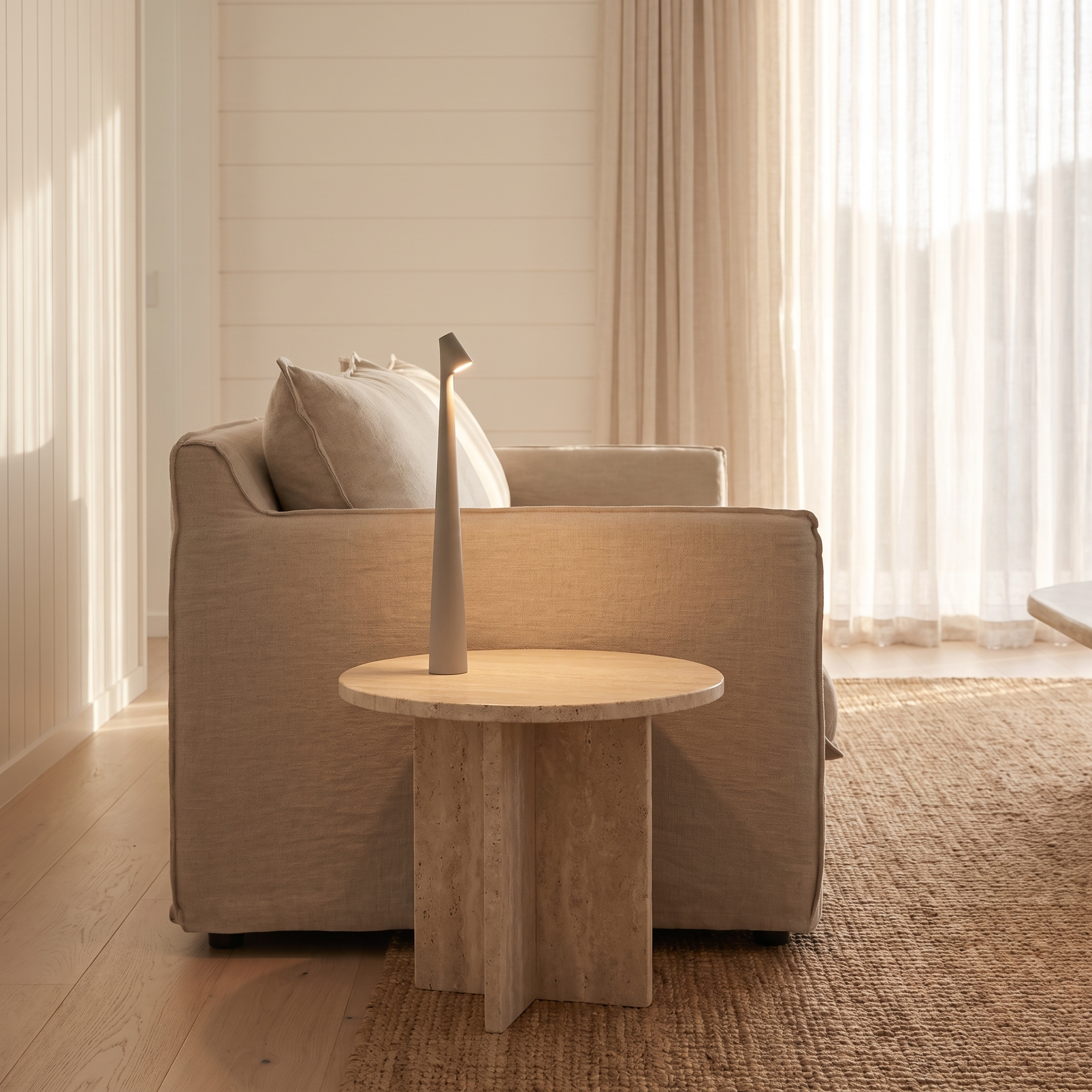 Massa cordless dimmable LED table lamp in Gray on a travertine side table beside a linen sofa
