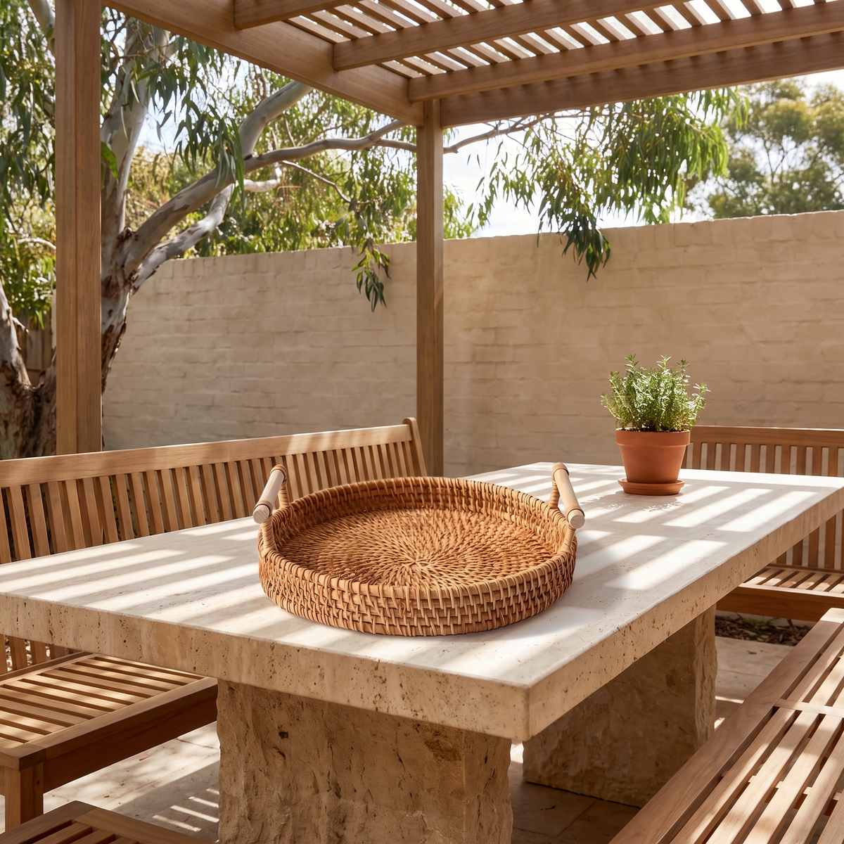 Mila Rustic Rattan Serving Tray on a travertine alfresco table under a pergola in dappled light