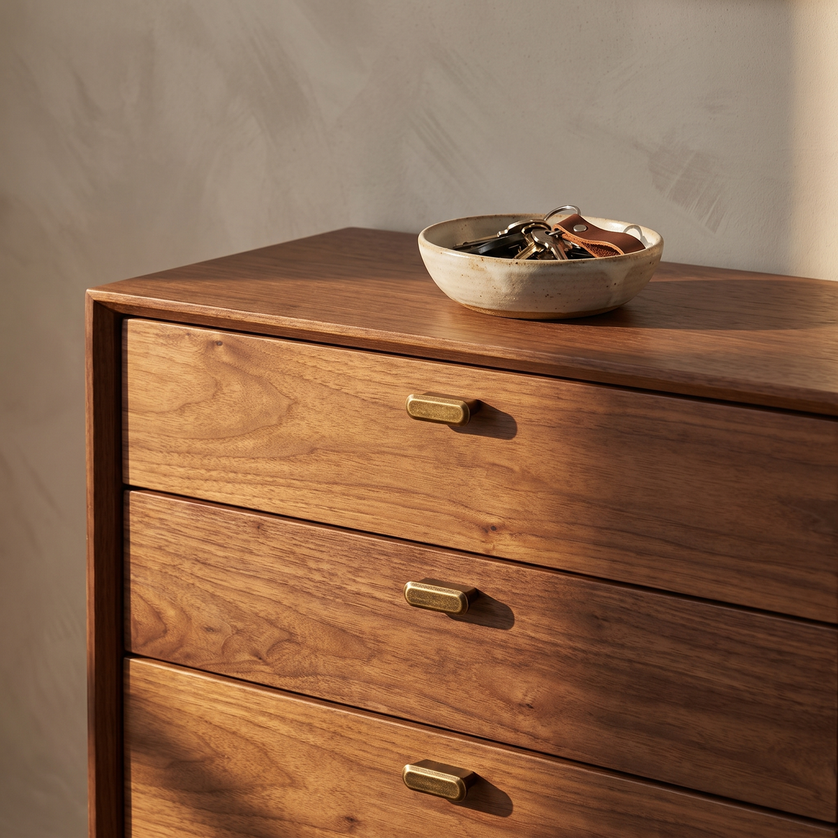 Murko antique bronze cabinet handles in small on a walnut chest of drawers in warm afternoon light