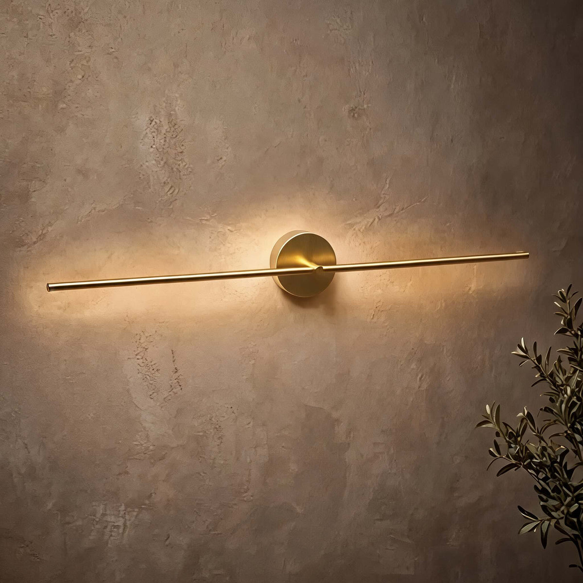Muxlow gold linear wall light casting a soft band of light across a textured plaster wall