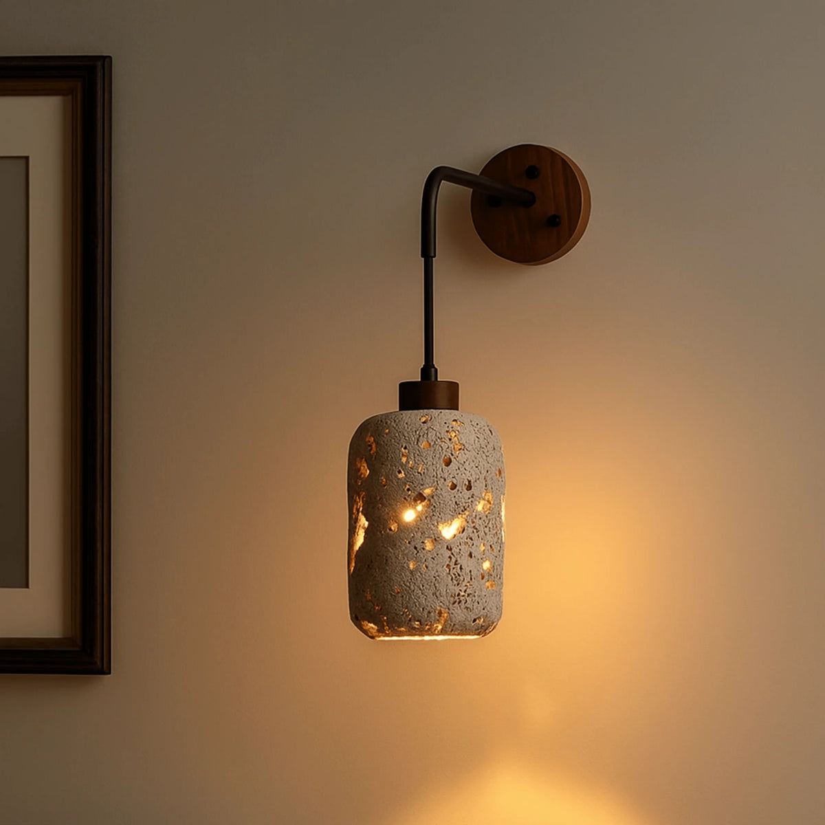 Nora travertine wall sconce lit on a wall, glowing through the pierced natural stone shade