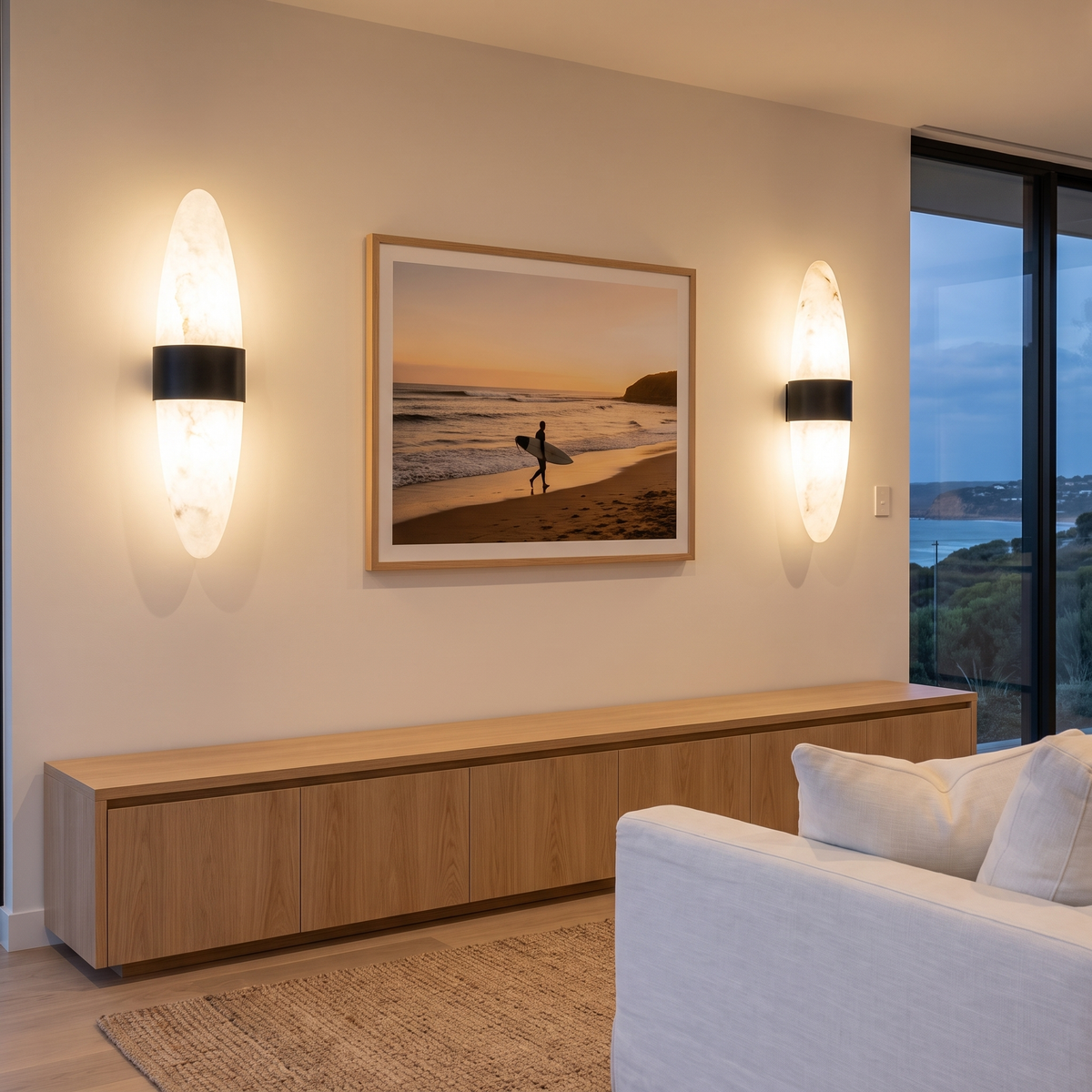 Pair of Nula alabaster wall lights flanking surf artwork in a coastal living room