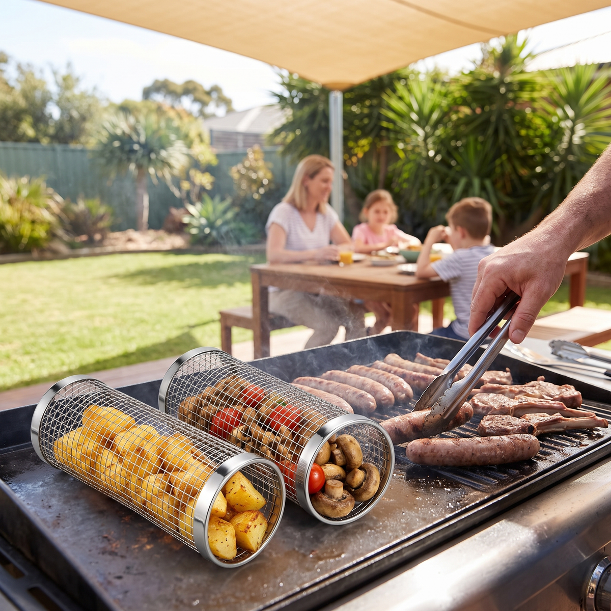 Prenta small rolling grilling baskets with potatoes and mushrooms beside sausages at a family backyard BBQ