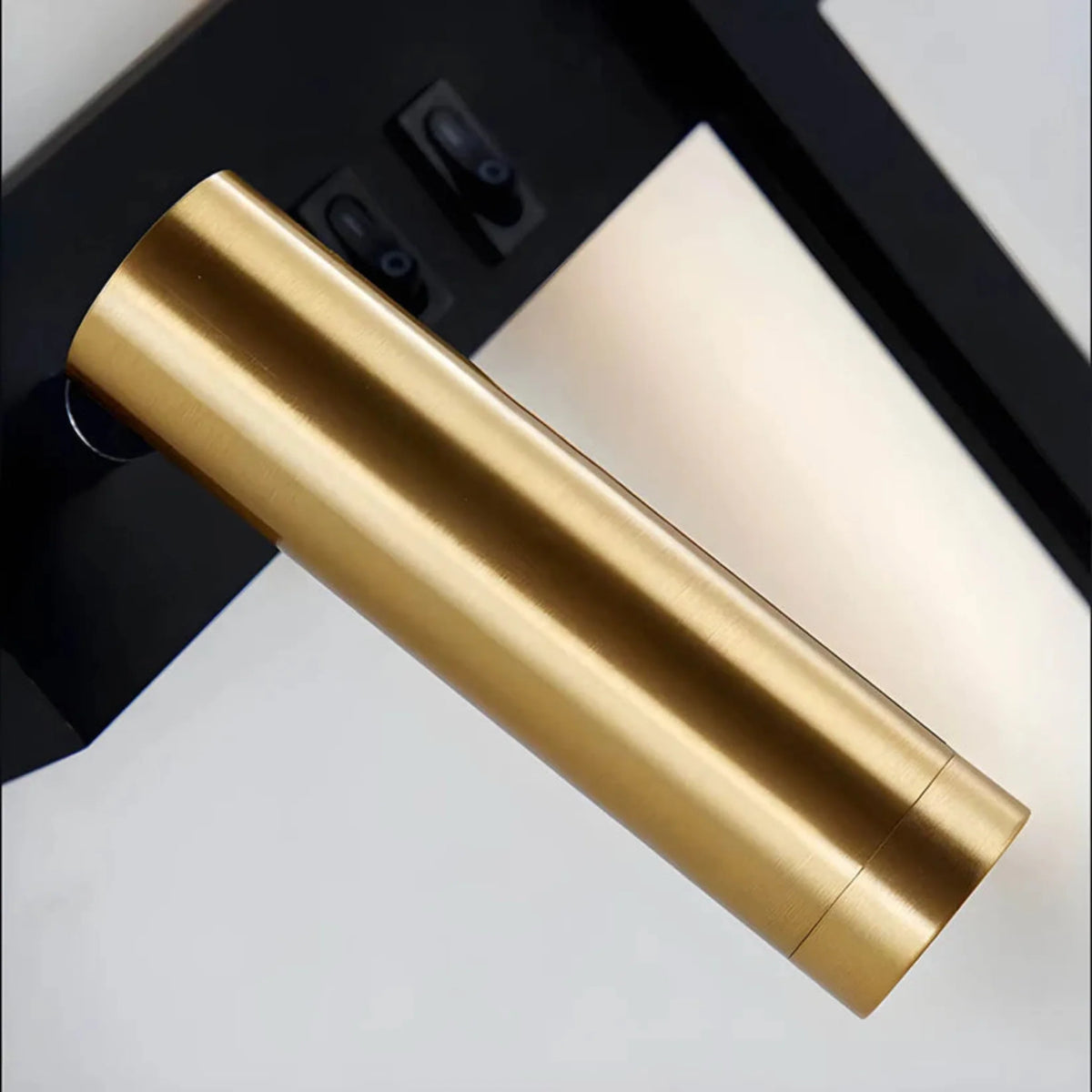 Preso LED wall reading light close-up of the brass spotlight and twin rocker switches