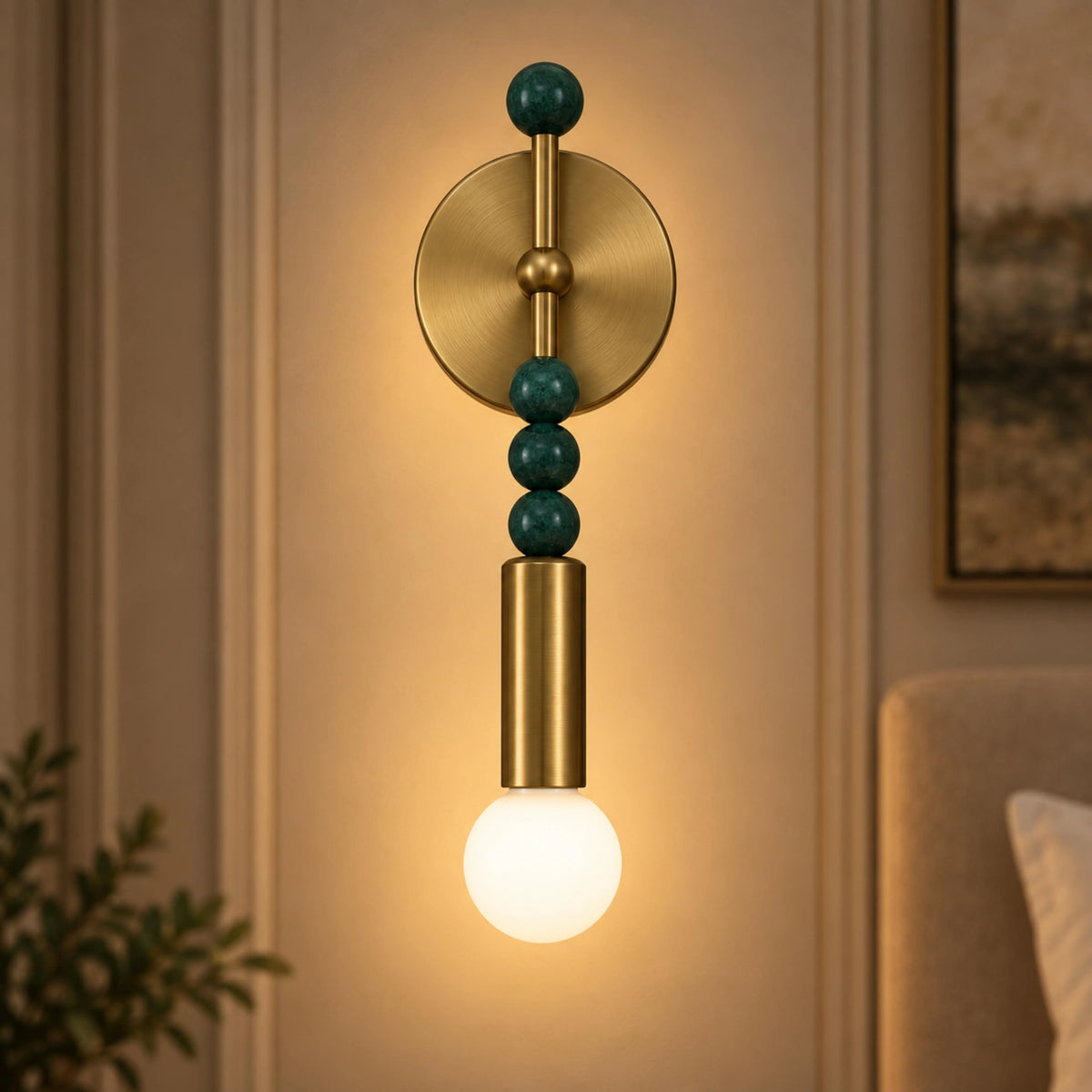 Sands brass wall sconce with green marble beads glowing beside a bedhead