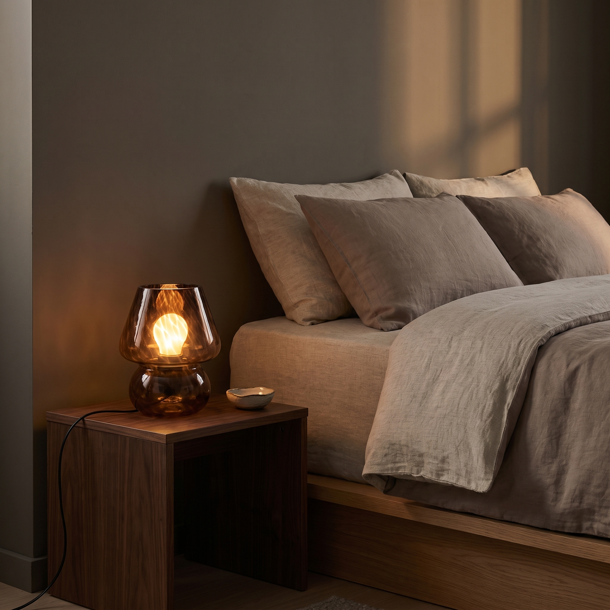 Sargi stained glass mushroom table lamp in brown glowing on a walnut bedside table