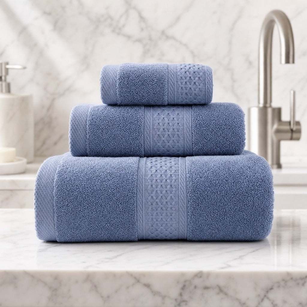 Serene cotton bath, hand and face towels in blue on a marble vanity by a chrome tap