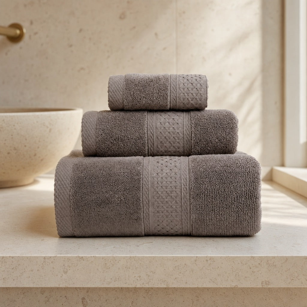 Serene 100% cotton bath towel set in brown stacked on a stone bathroom bench