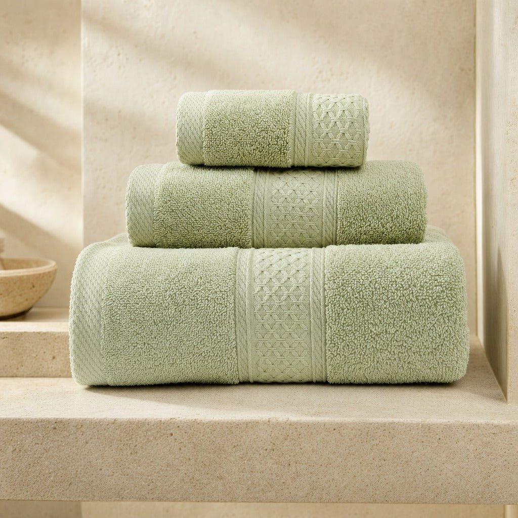 Serene cotton bath, hand and face towels in green stacked on a pale stone bench