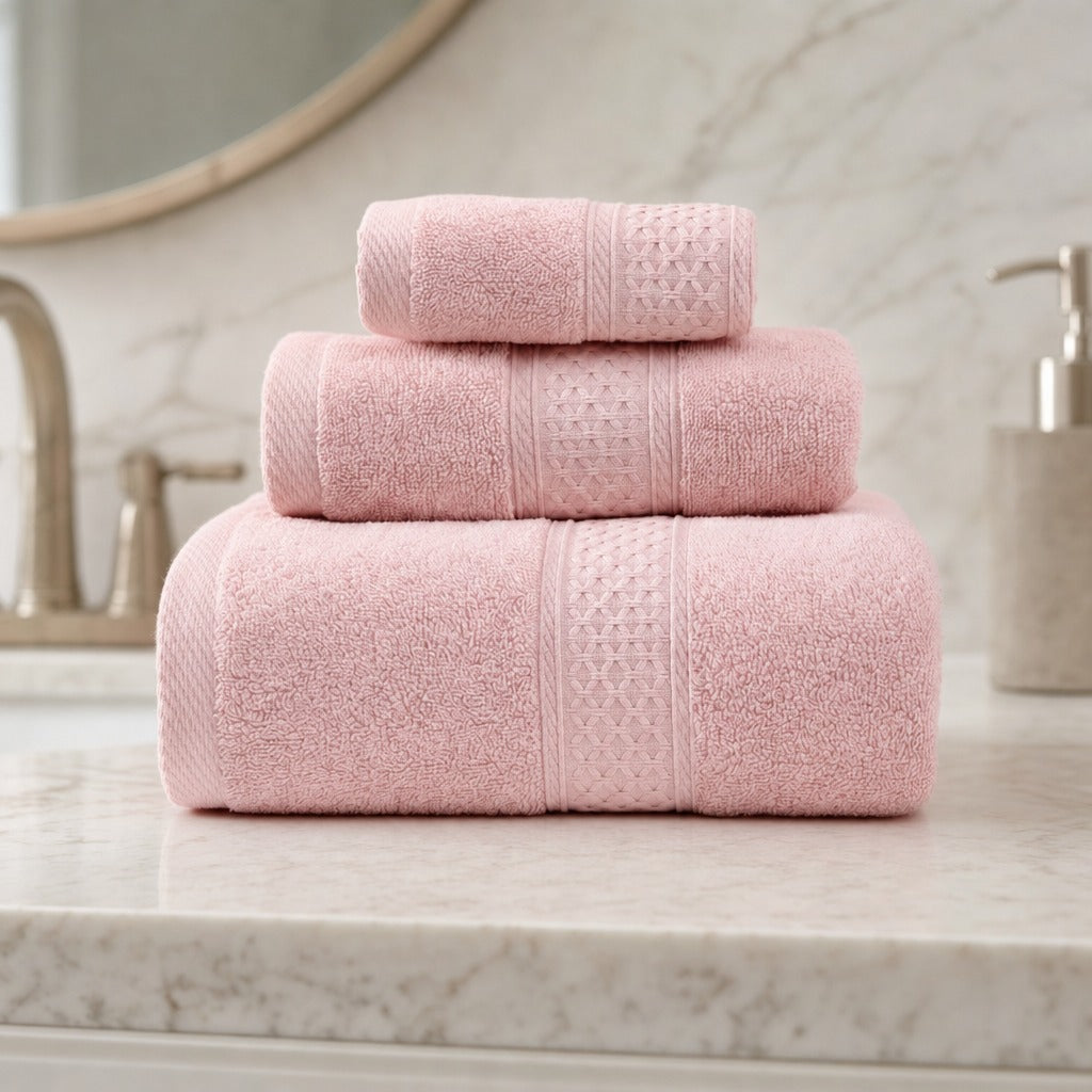 Serene 100% cotton bath towels in pink stacked on a marble vanity beside a brass tap