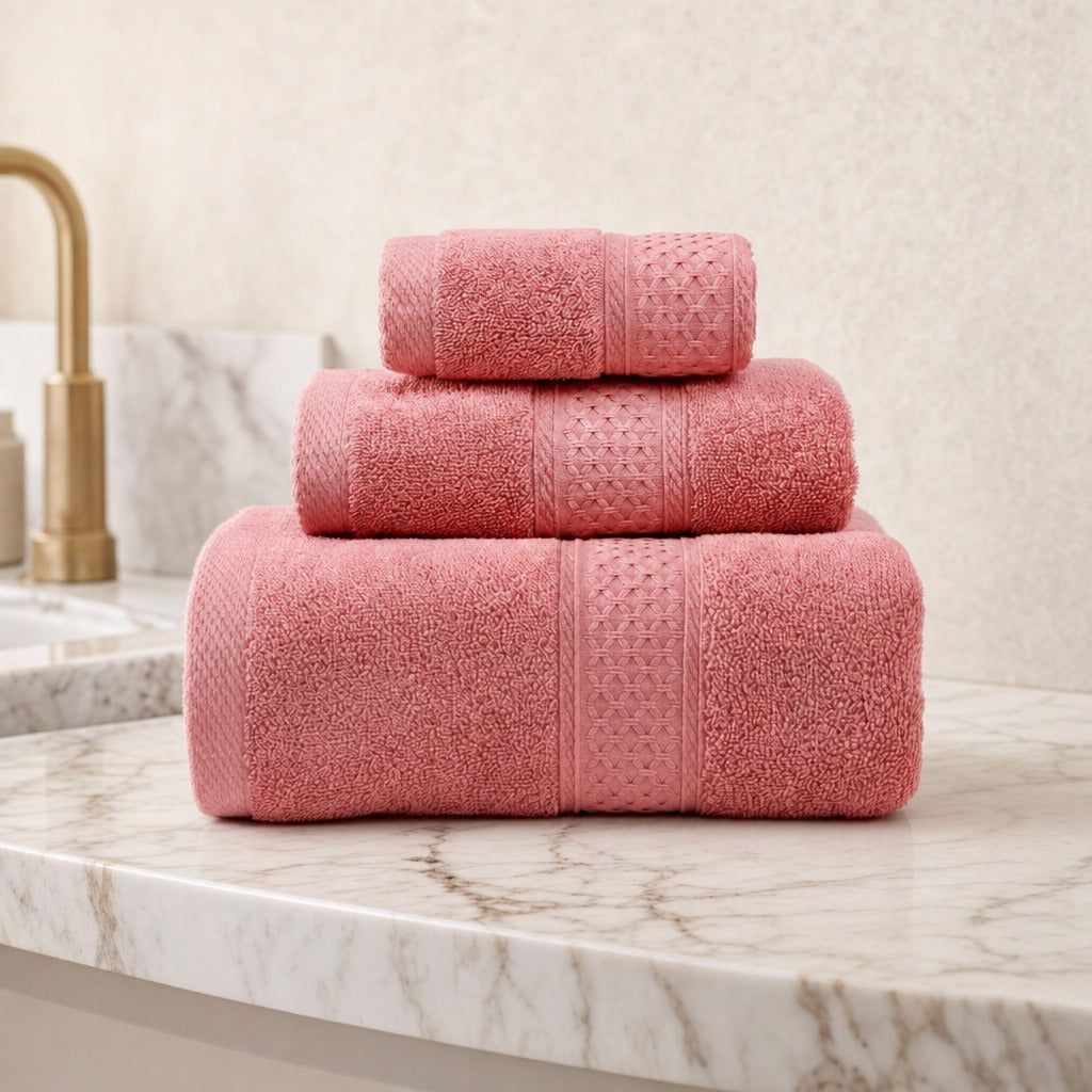 Serene 100% cotton bath towels in red stacked on a marble vanity beside a brass tap
