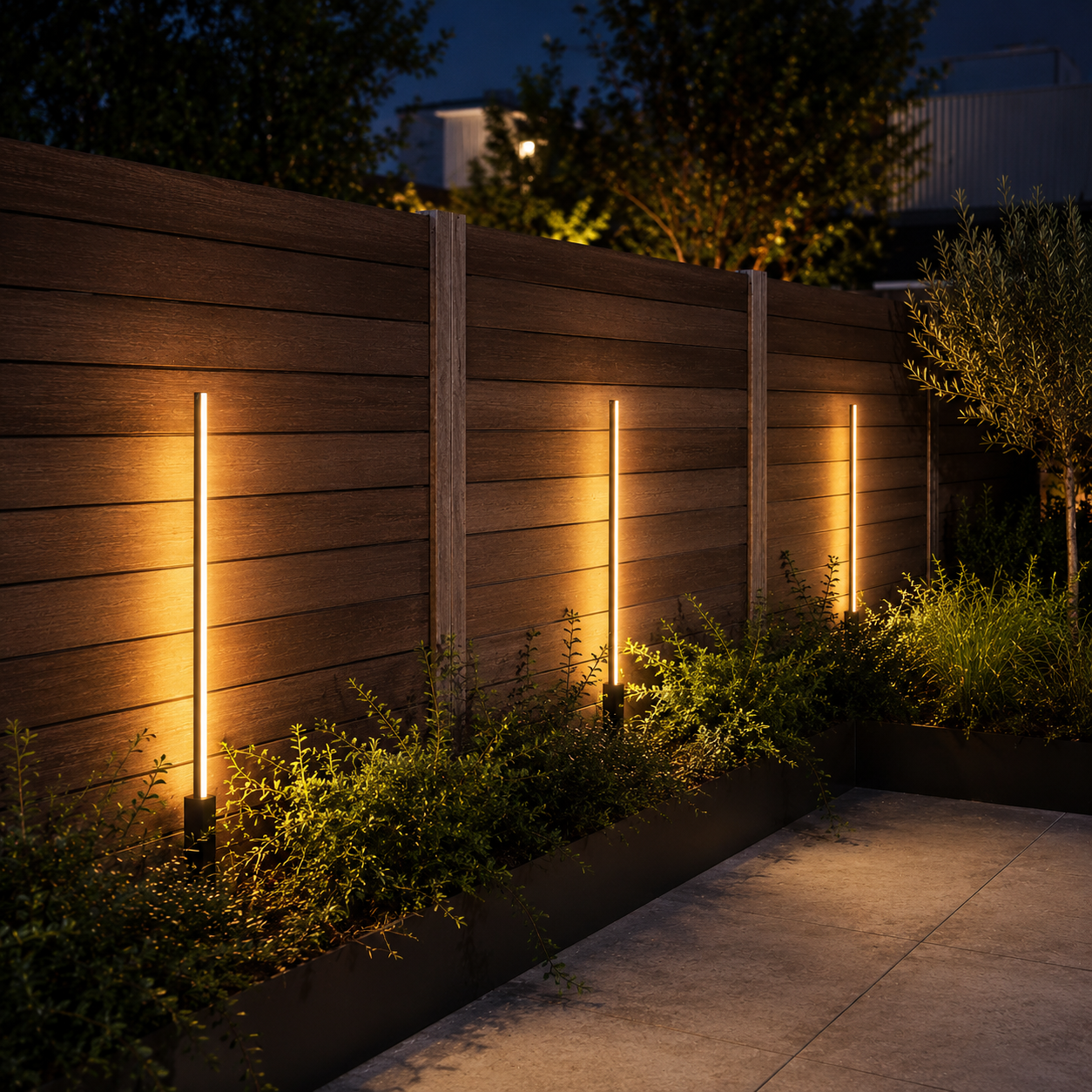 Sienna LED Garden Bollard Light illuminated at night in a courtyard
