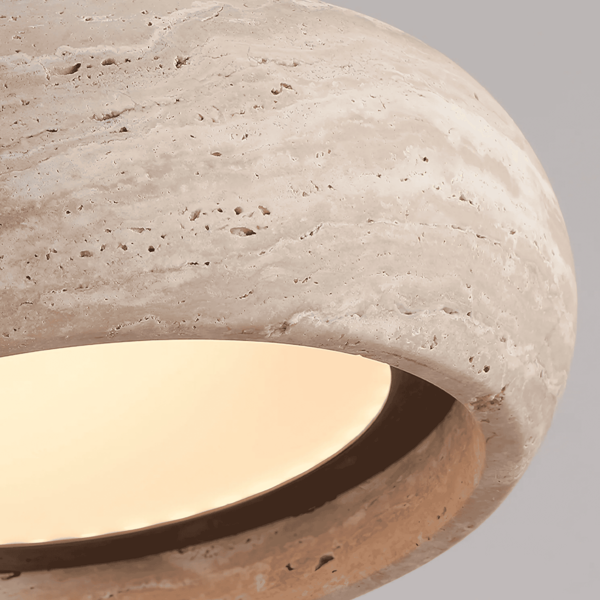 Close-up of Sora travertine pendant light showing natural stone veining, pitting and warm LED glow