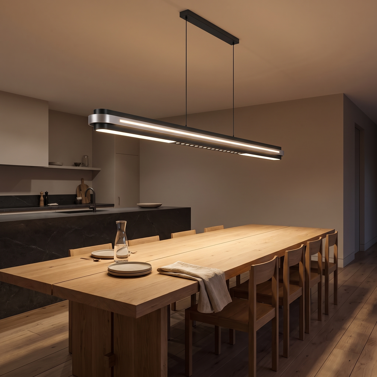 Spice linear LED pendant light lighting a long oak dining table in an open-plan kitchen at night