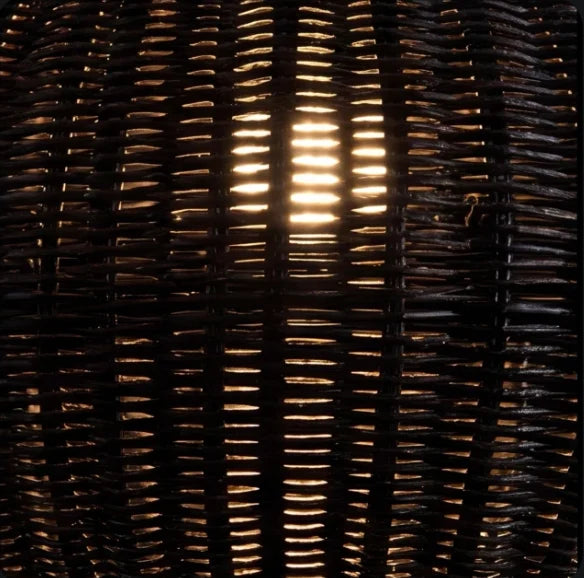 Close-up of the Suka pendant's black woven synthetic rattan shade with warm light glowing through