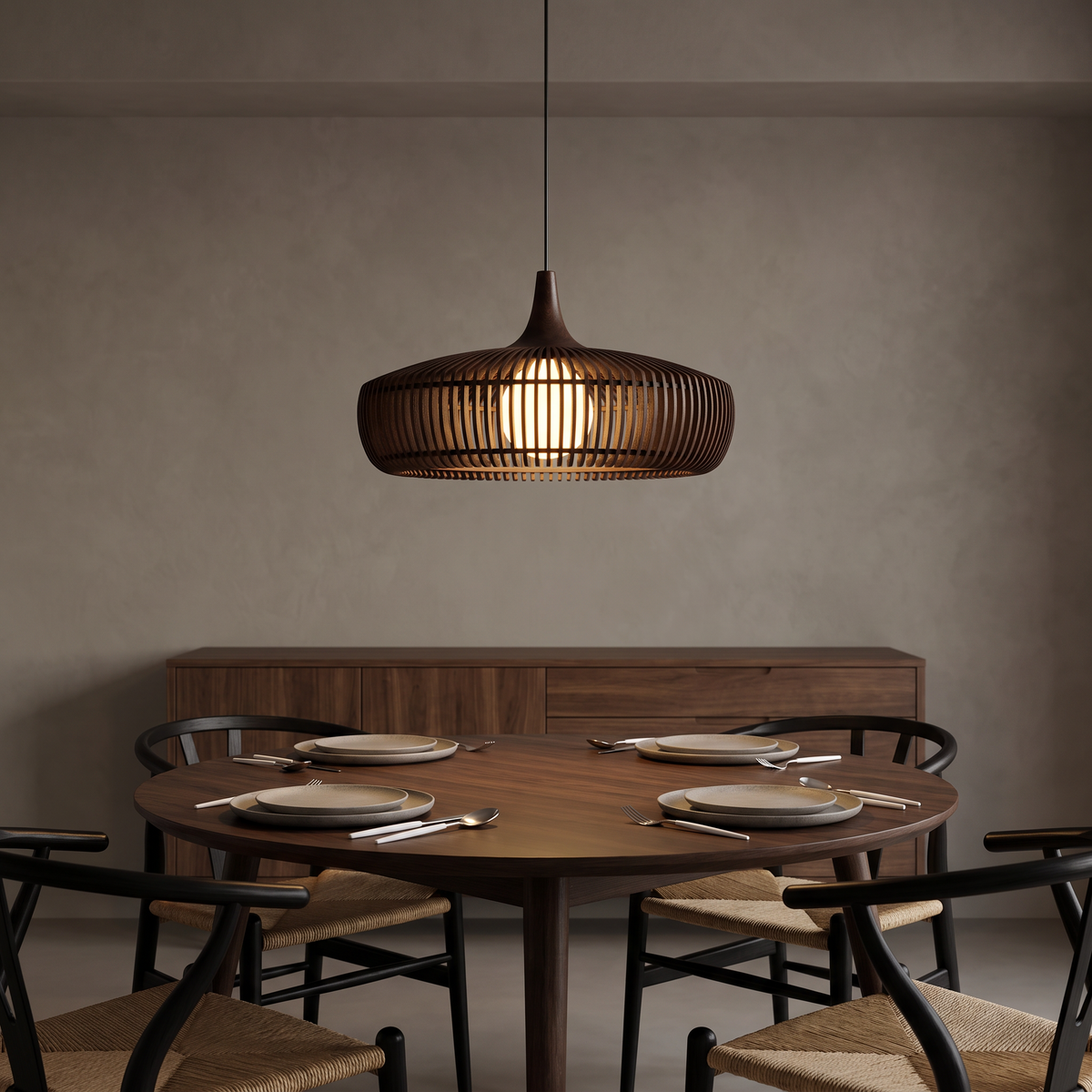 Walnut Talandji pendant glowing over a round dining table set with Dorsia white handle cutlery