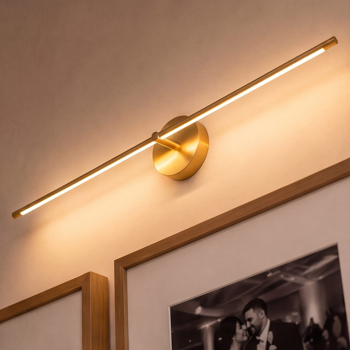 Tomi linear wall sconce in gold mounted as a picture light above framed artwork