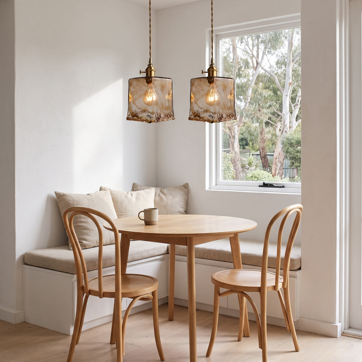 Pair of Tooky Model C amber glass pendants over a round oak table in a breakfast nook