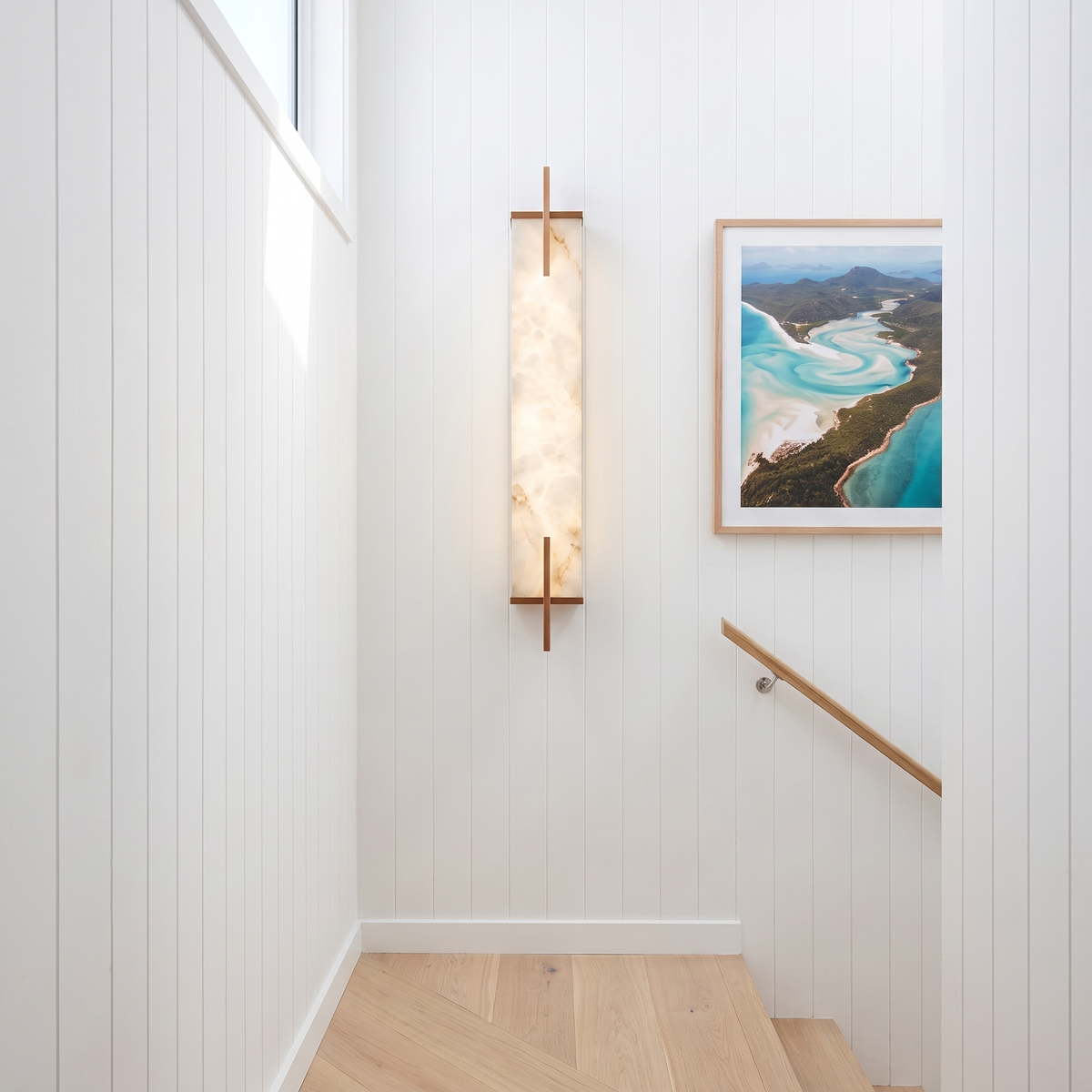 Tyla alabaster wall sconce with copper finish on a coastal staircase landing