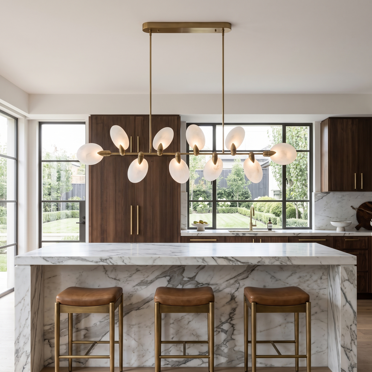 Vale modern chandelier running the length of a Calacatta marble kitchen island with leather stools
