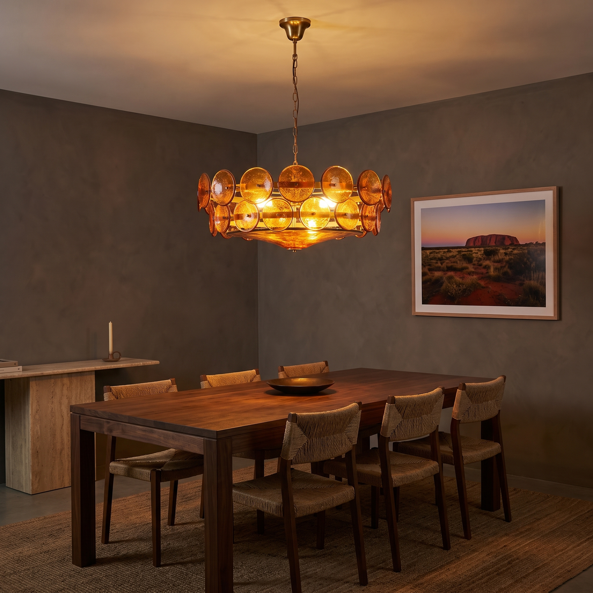 Yarra Retro Glass Chandelier in orange glowing over a walnut dining table at night