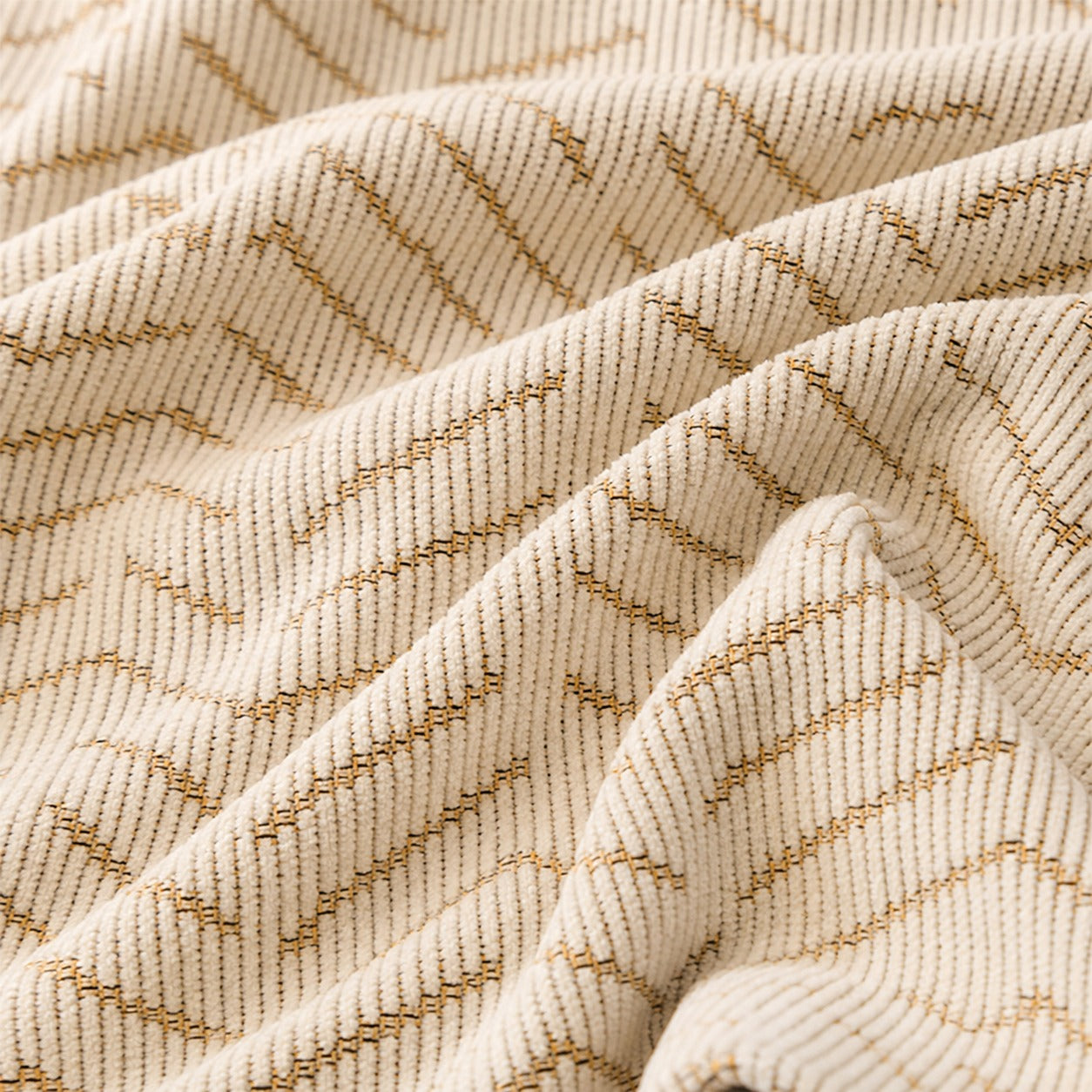 A close-up of a textured knit fabric in cream with a woven geometric pattern in tan.