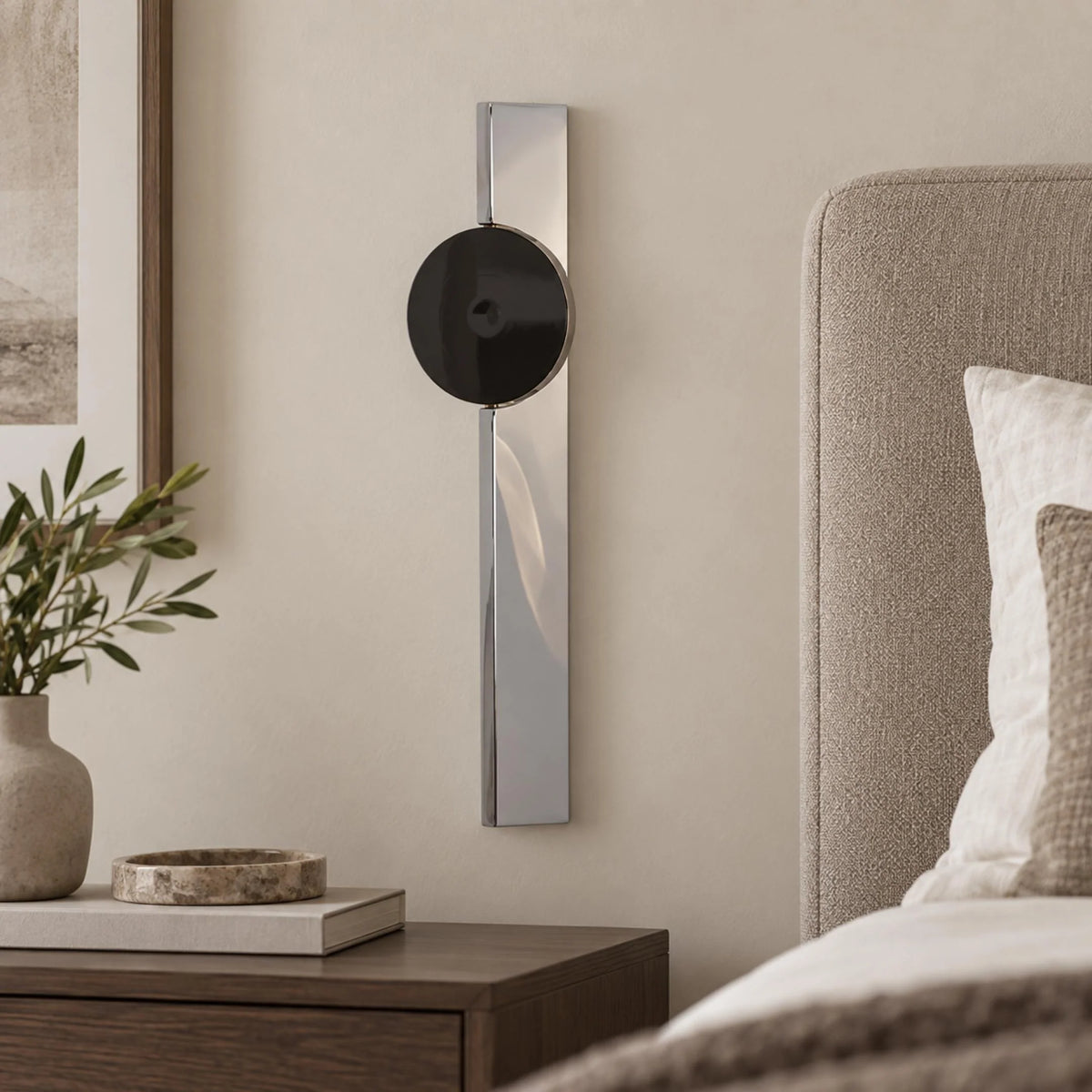 Alya mirrored chrome and black disc wall sconce beside a bed and timber bedside table