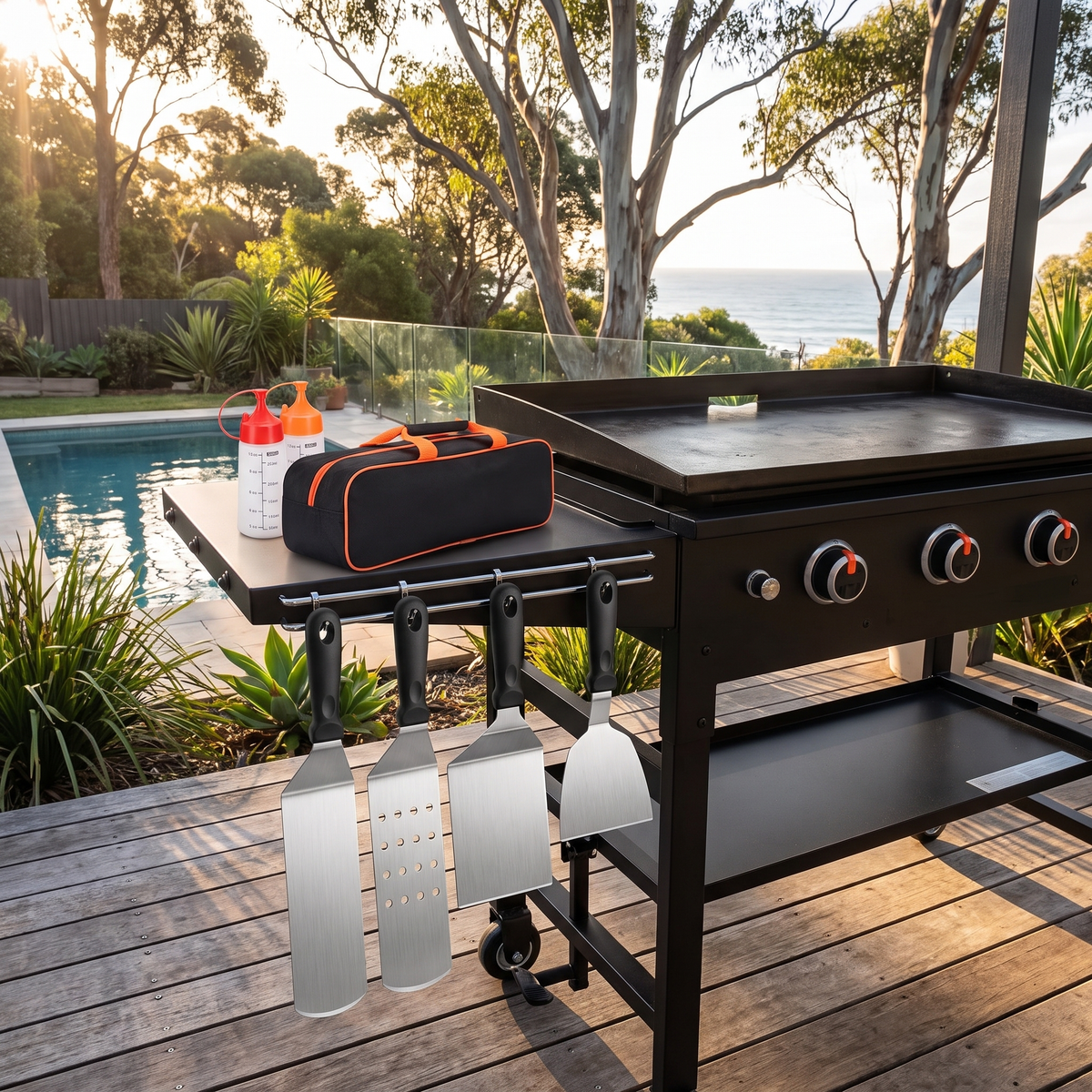 Angus BBQ accessories set spatulas hanging on a flat-top griddle by the pool at sunset