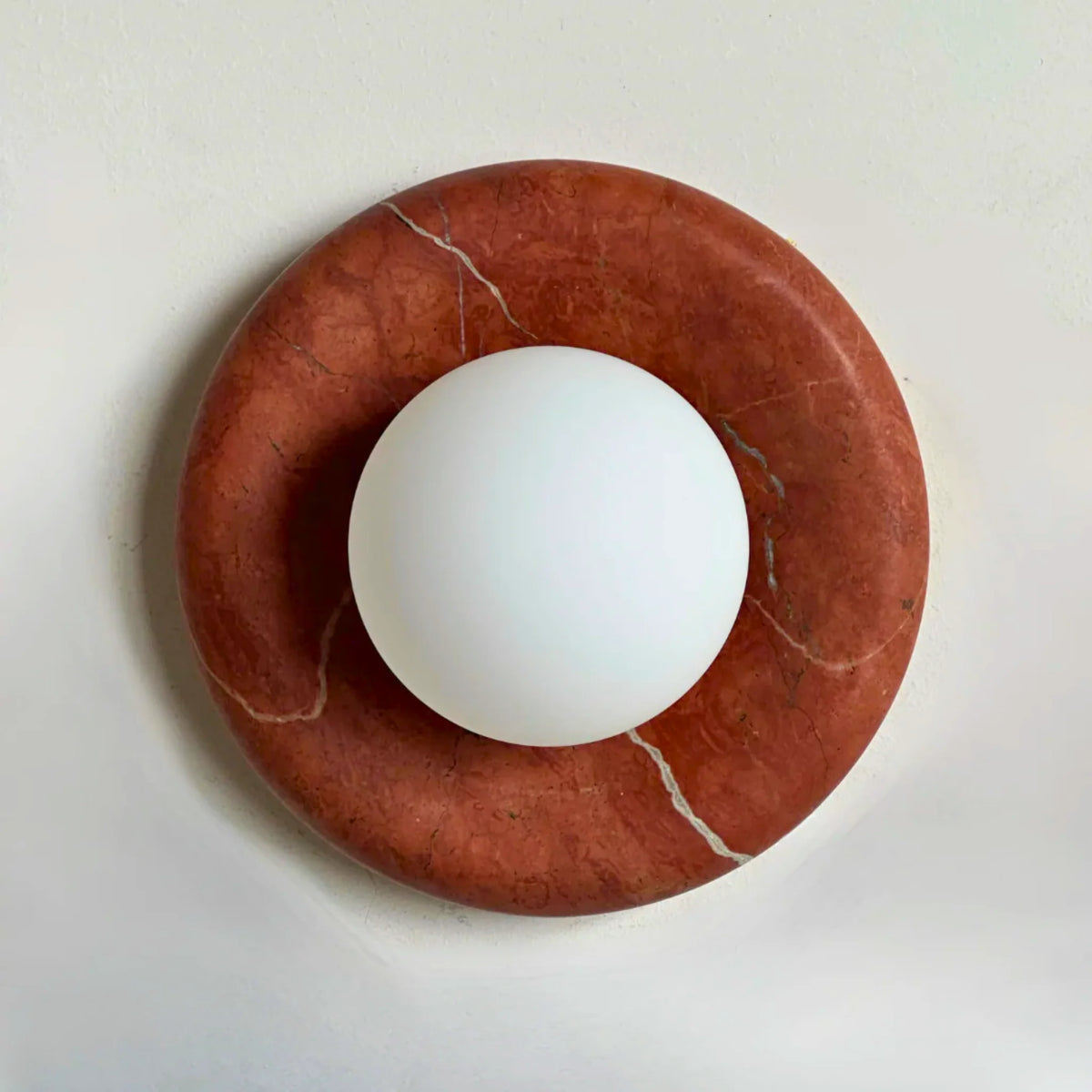 Aril marble wall sconce with a red marble ring and frosted opal glass globe