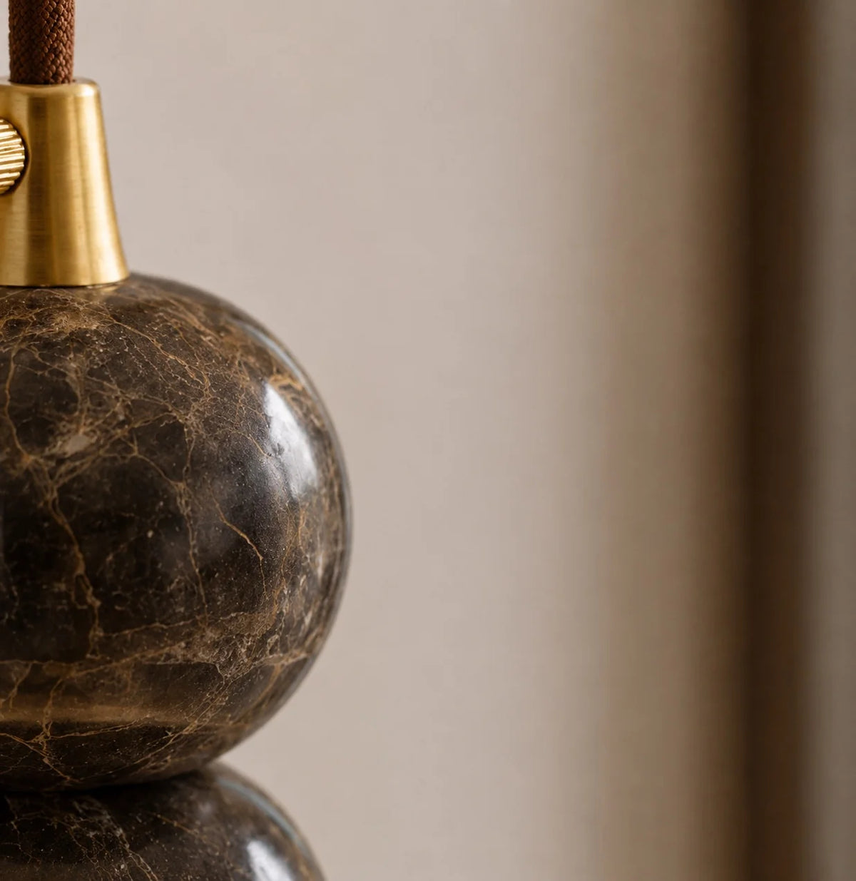 Close-up of a Banyjima pendant's dark veined marble sphere above the faux alabaster shade