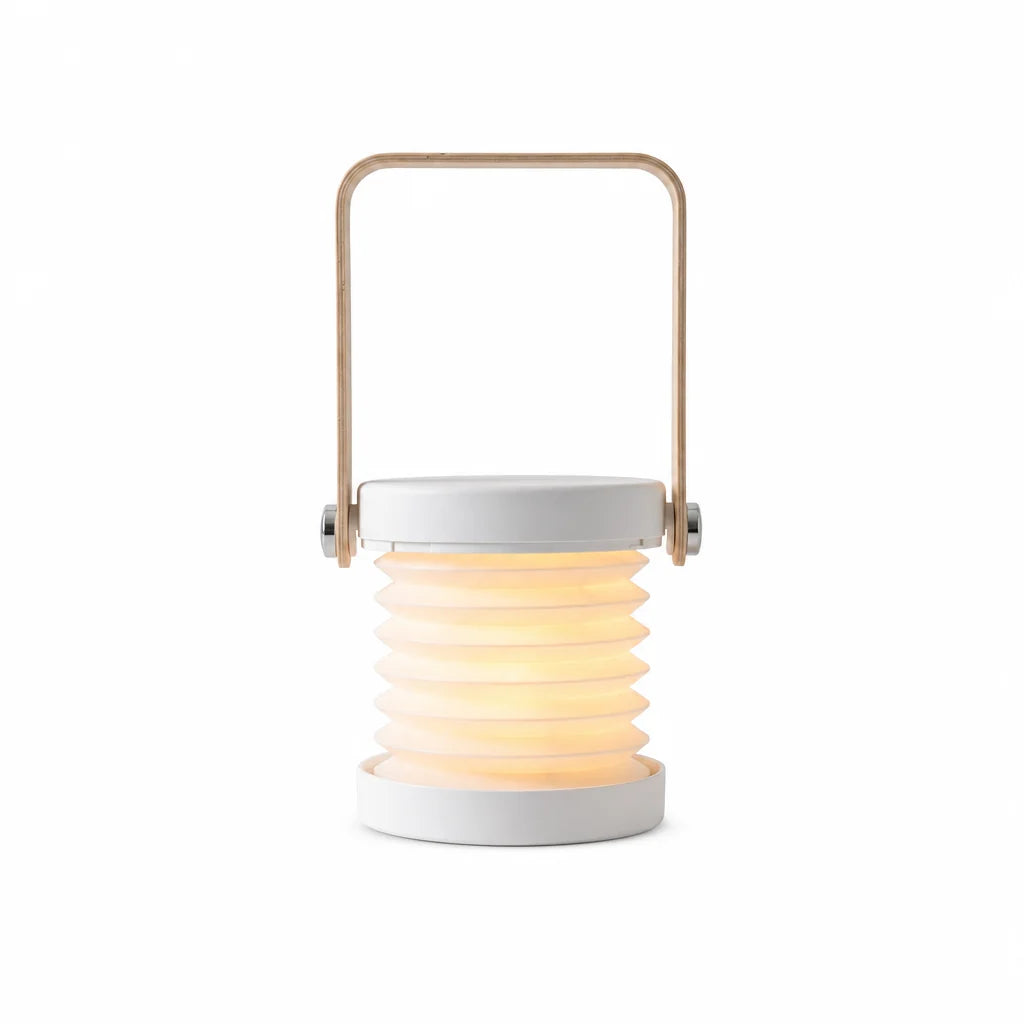 Brae folding travel lantern in white with birch handle, opened and lit, on a white background