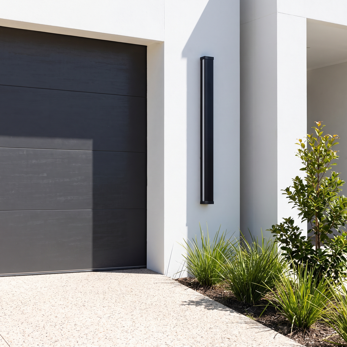 Burdekin RGB LED outdoor wall light, 120cm, in black beside a charcoal garage door by day