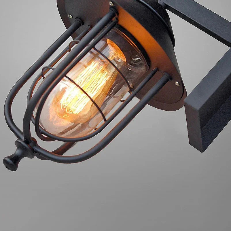 Cala Iron & Glass Outdoor Wall Light illuminated at dusk near a doorway