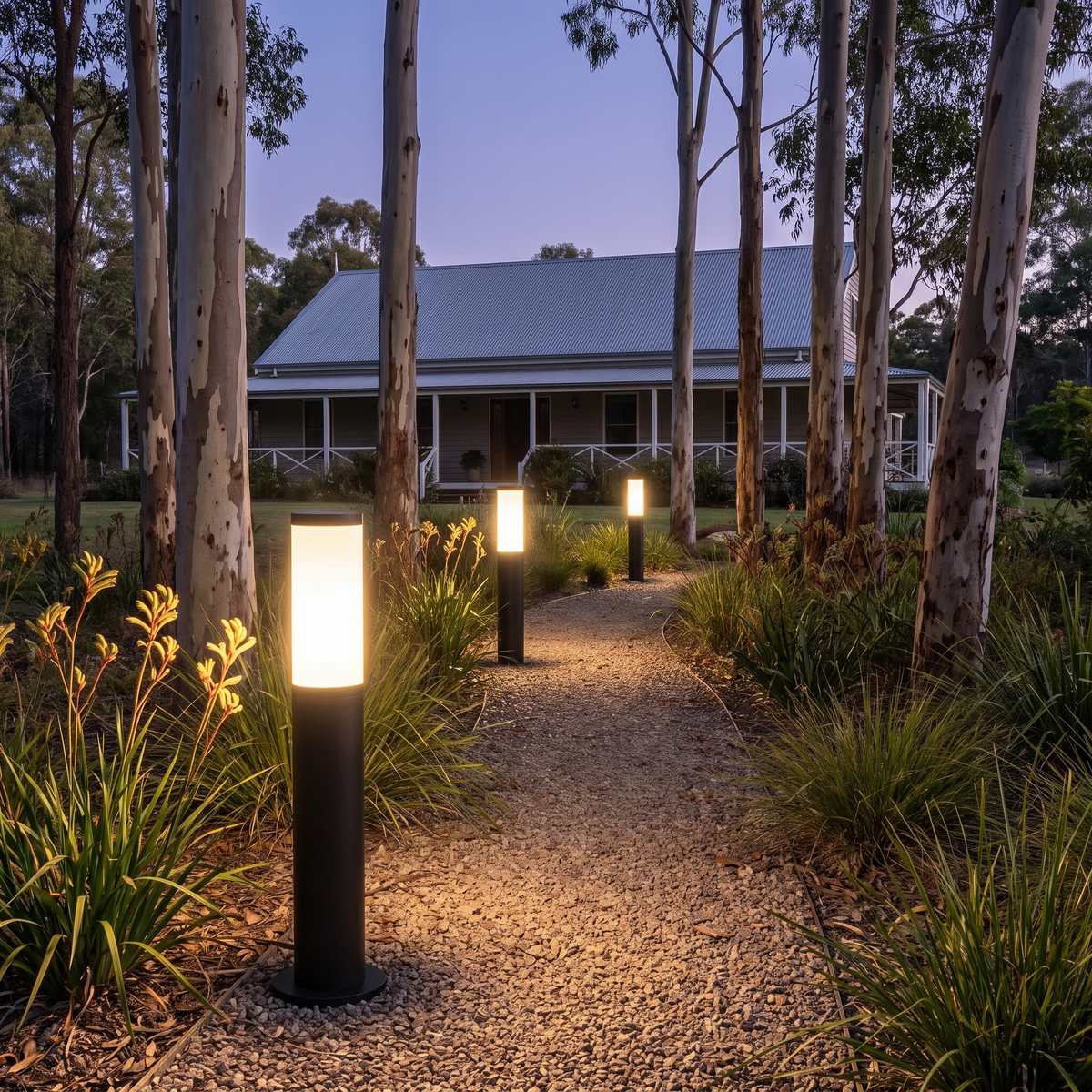 Three 99.1cm Clancy waterproof bollard lights along a gravel driveway to a hinterland farmhouse at dusk