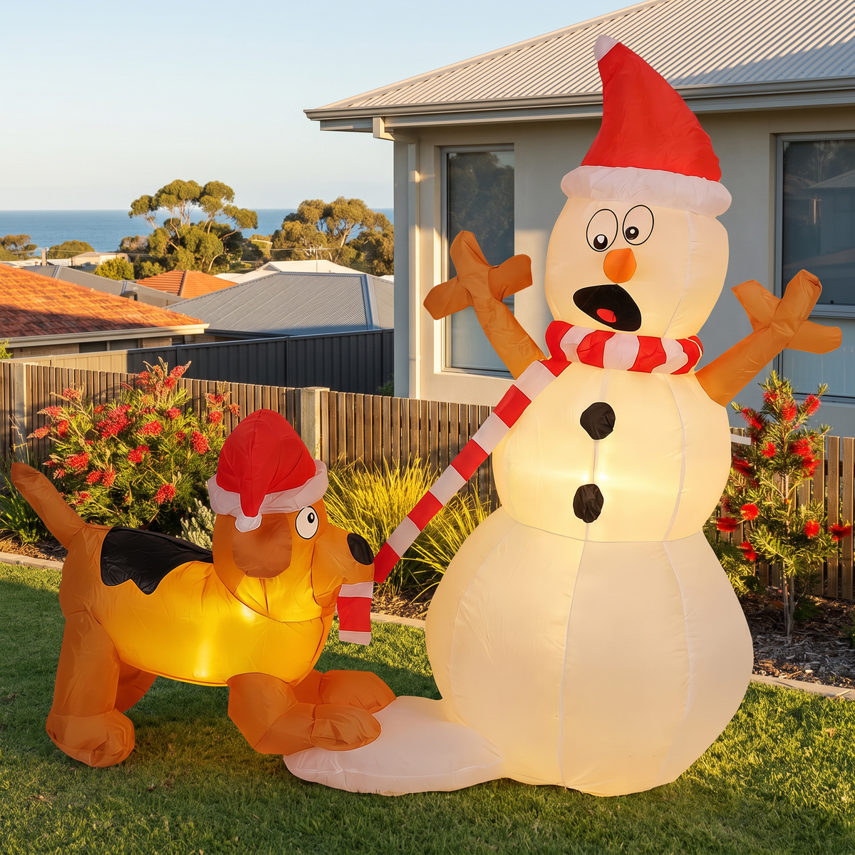 Claus inflatable snowman and dog on a front lawn with ocean views at golden hour