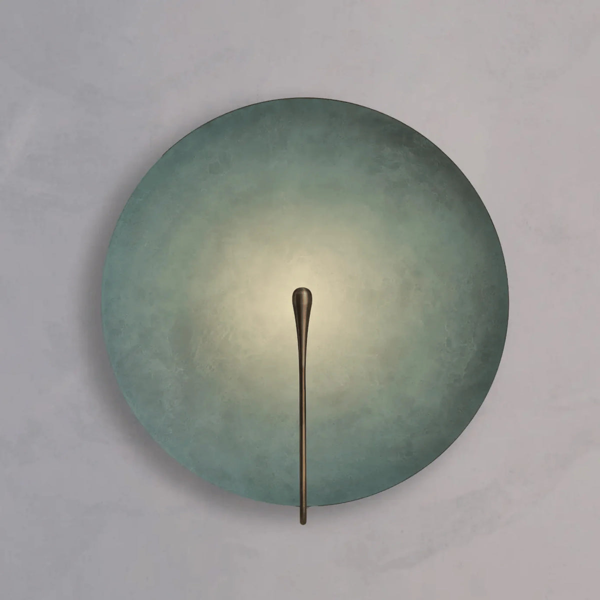 Clyde stainless steel round wall light in the light green-blue finish lit on a wall