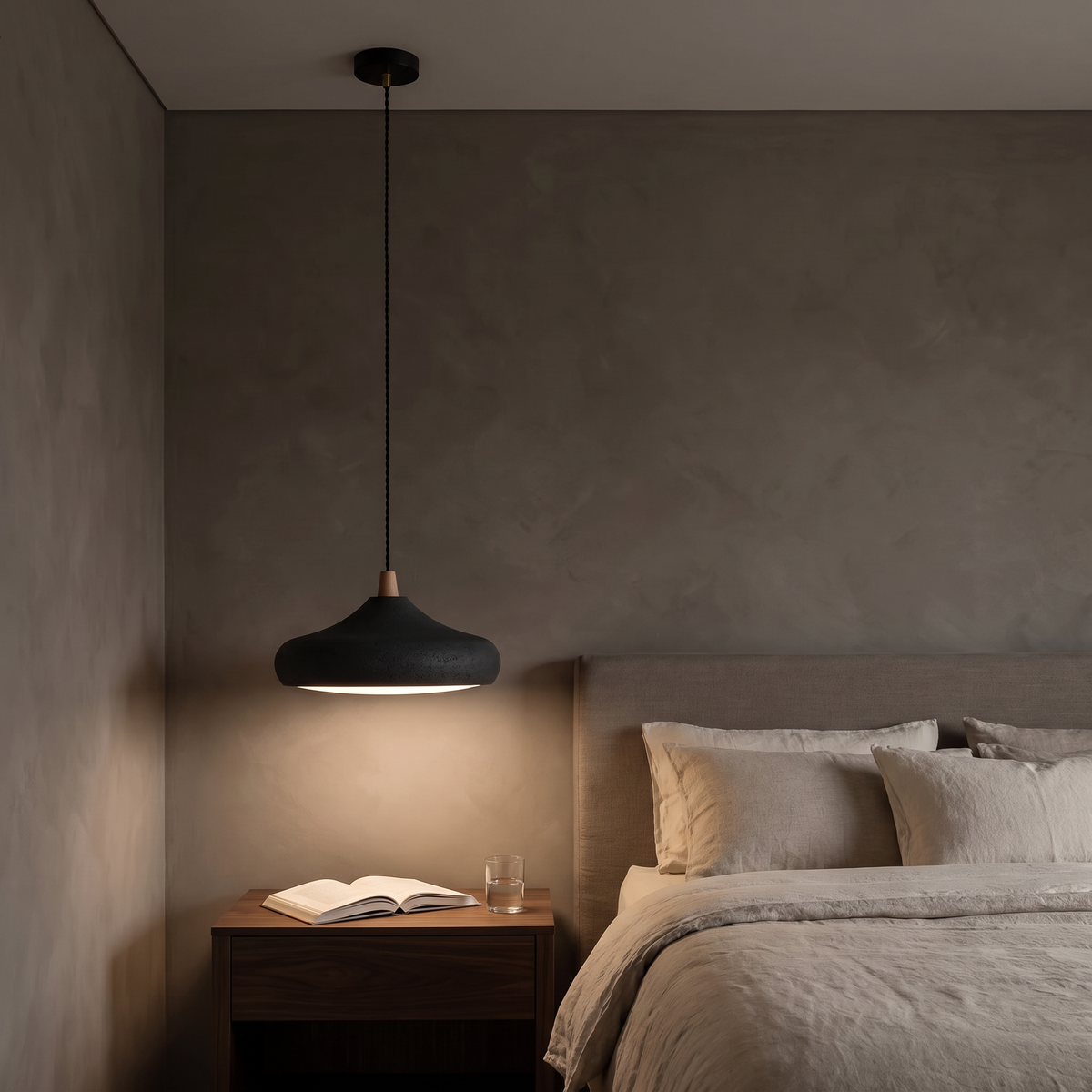 Dakota black disc pendant light hanging beside a bed as a bedside light