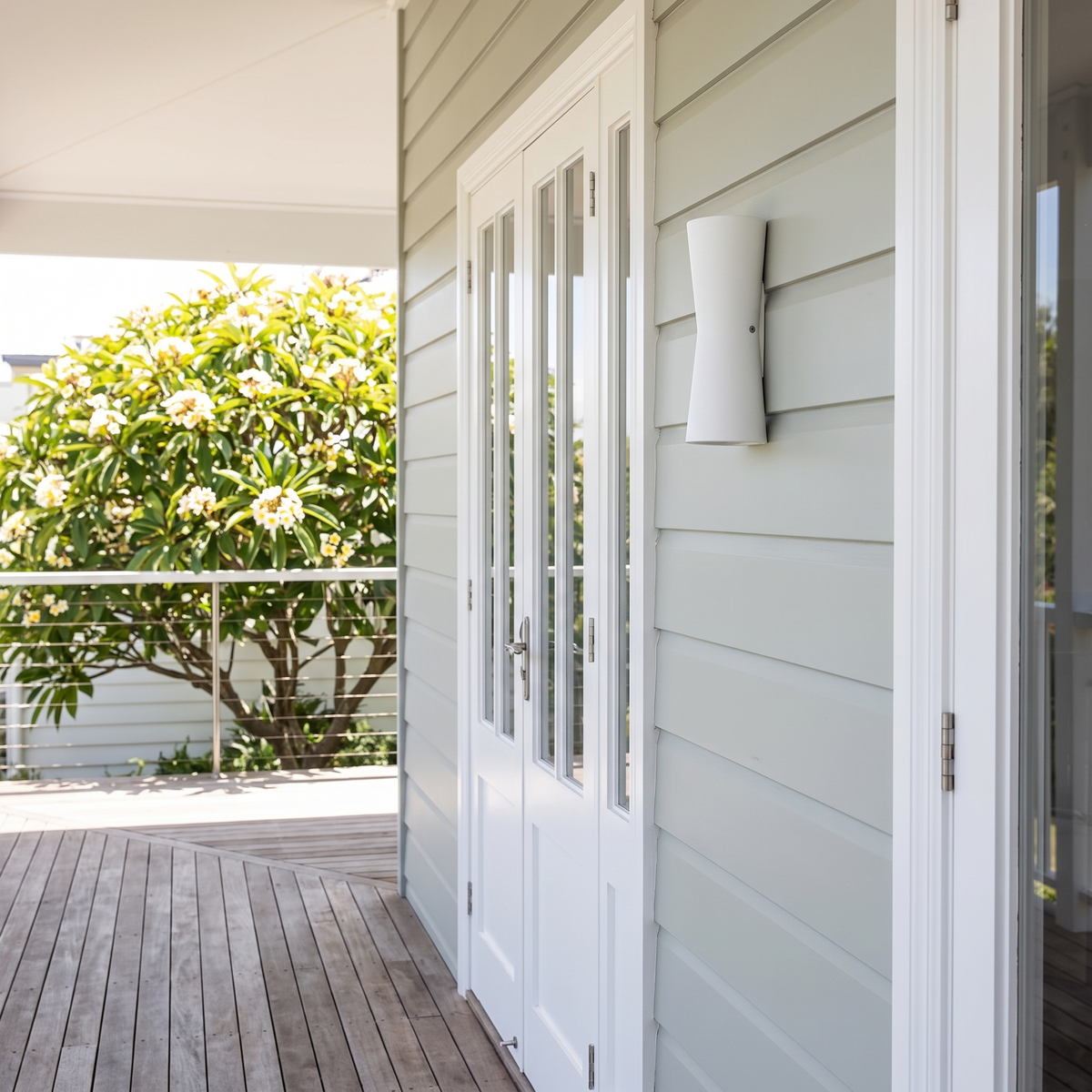 Dewy torch-style outdoor wall light in white on a sage weatherboard beach house verandah