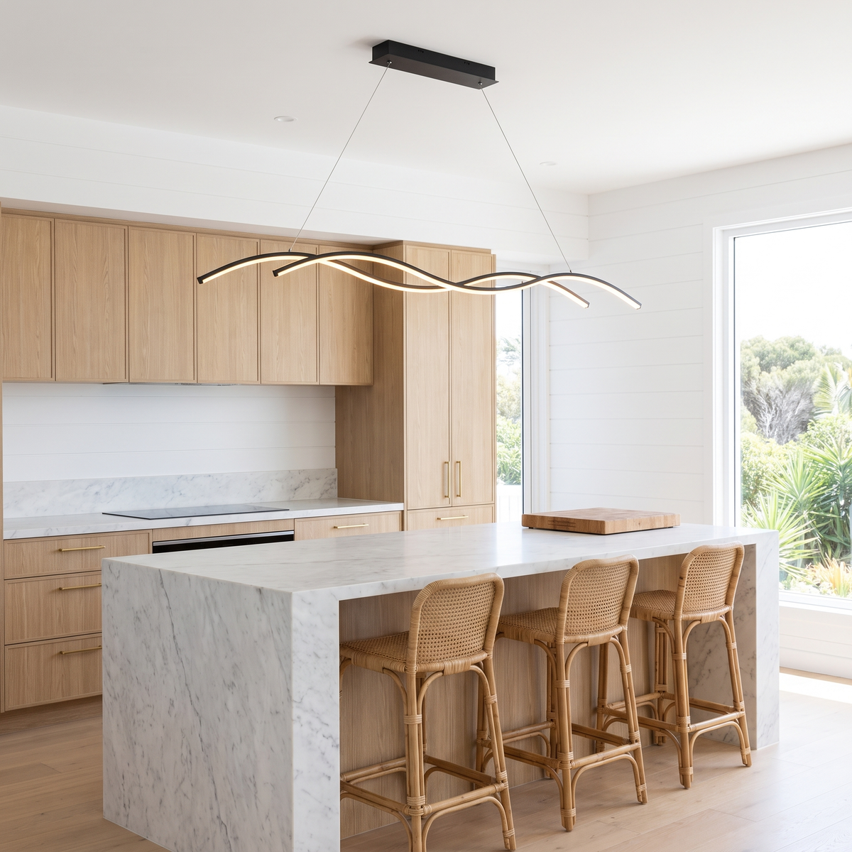 Grajagan black wave pendant light over a marble kitchen island in a bright beach house