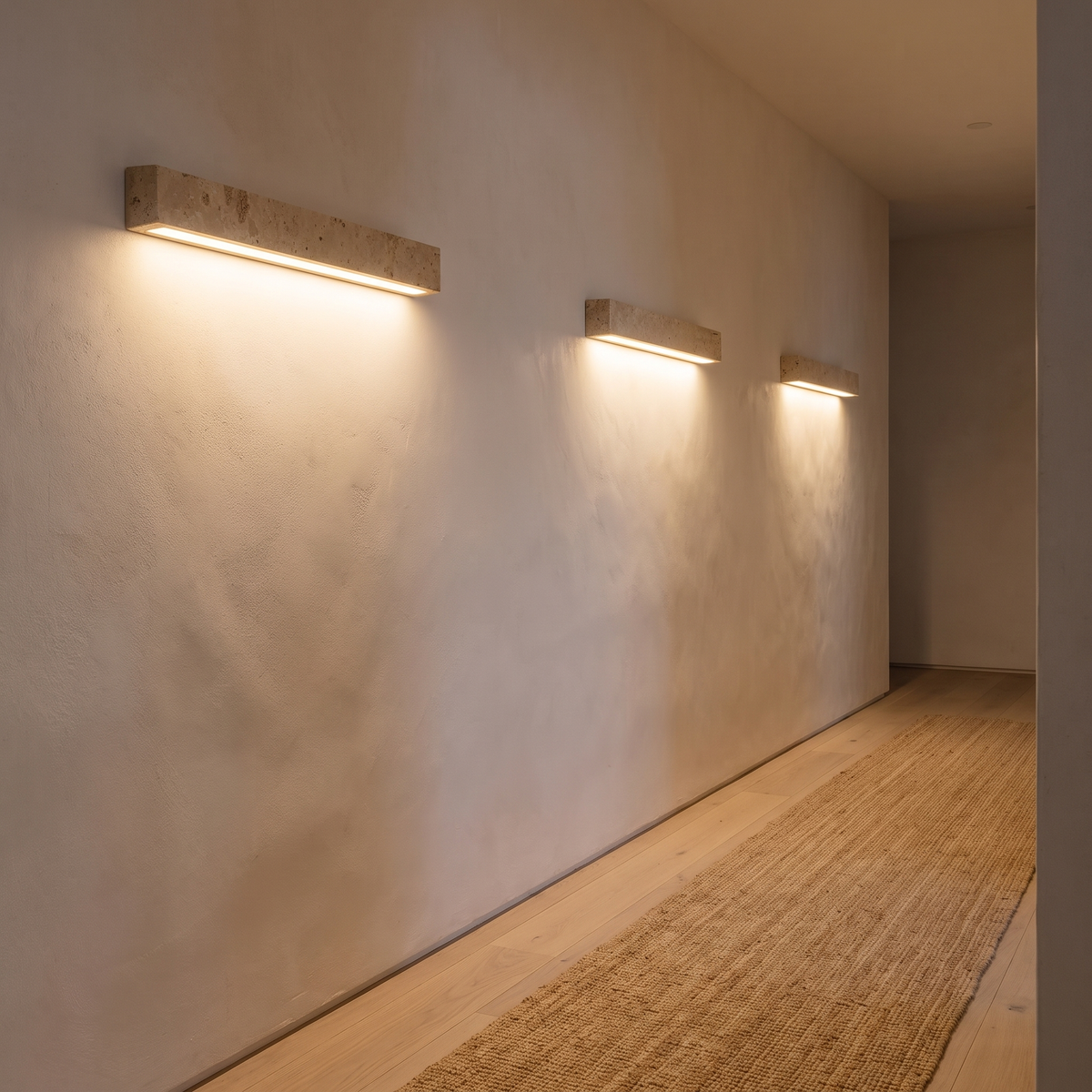 Three Guru travertine wall lights casting down light along a hallway