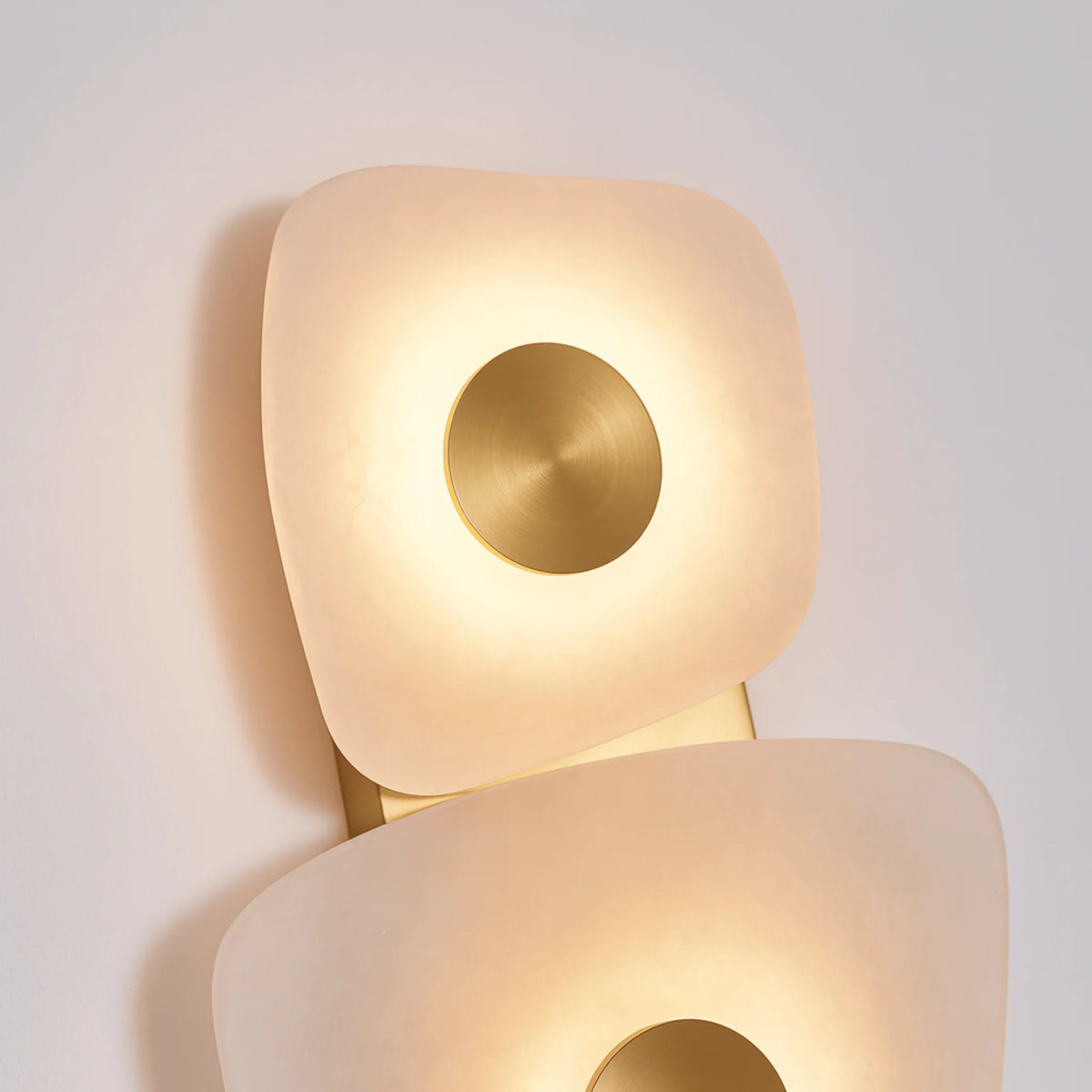Harbord marble wall sconce close-up of the glowing marble panels and brushed brass discs