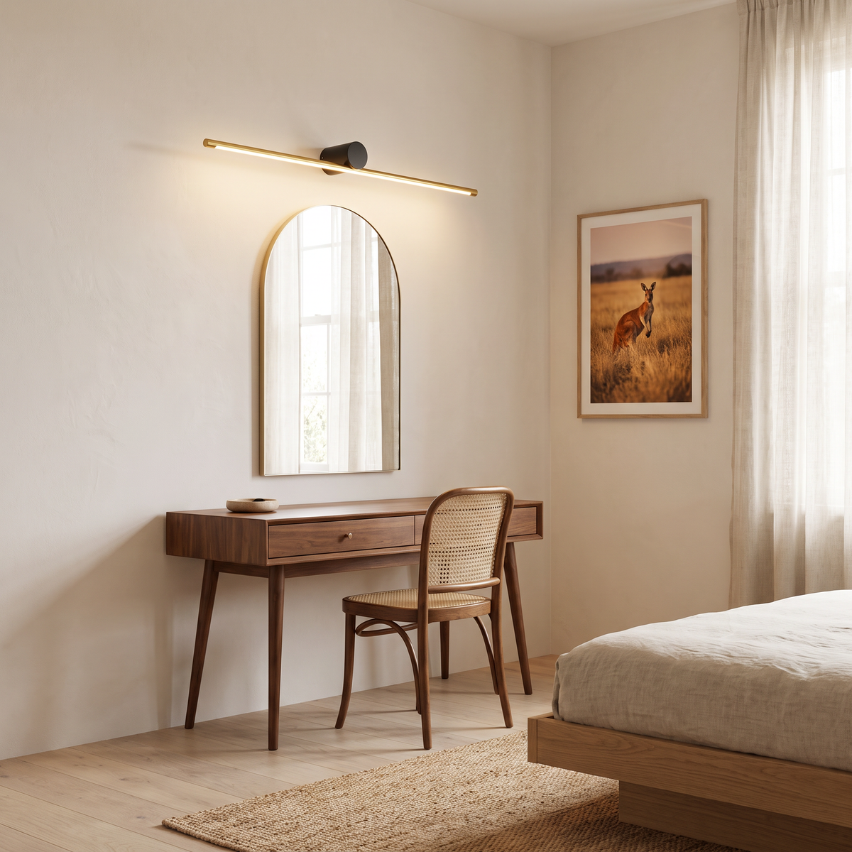 Gold and black Hartog light bar above an arched mirror and walnut dressing table in a bedroom
