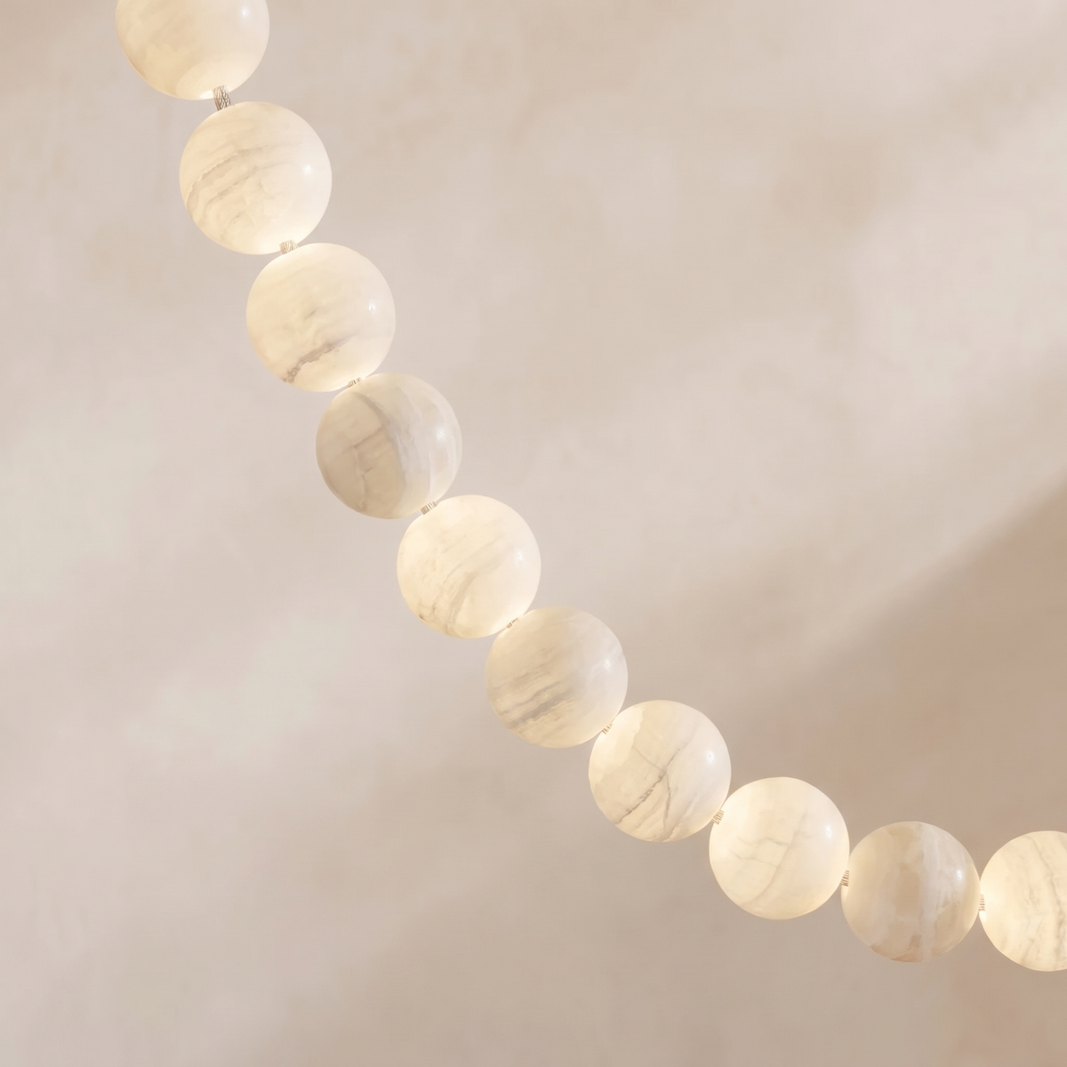 Close view of the Jawa pendant's pale ivory alabaster beads and their soft warm white glow