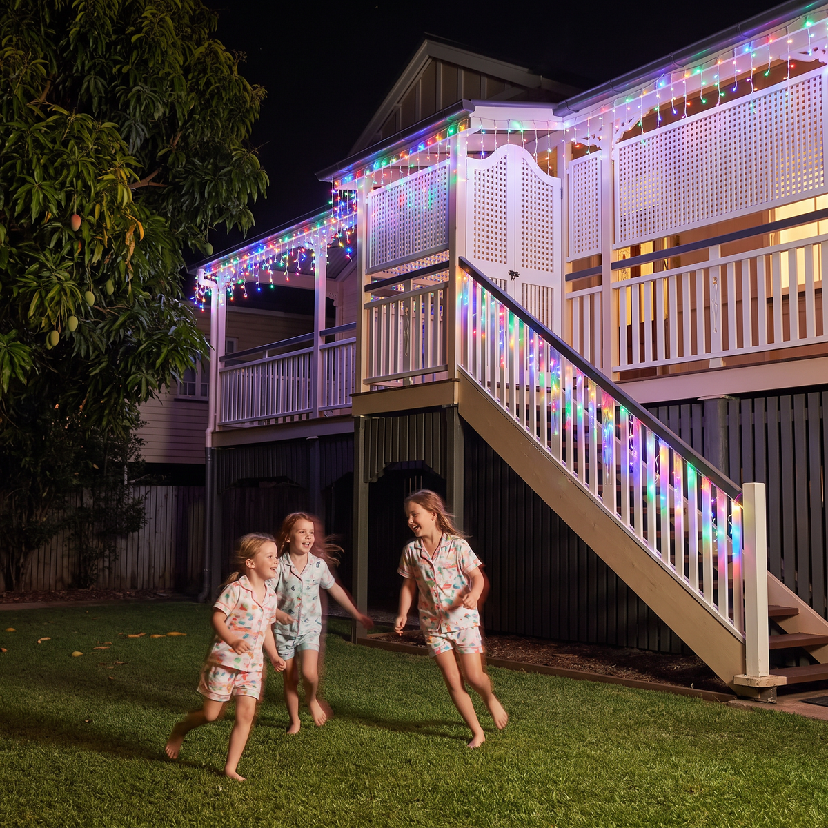Jingle LED icicle lights in multicolour on a Queenslander verandah with kids at night