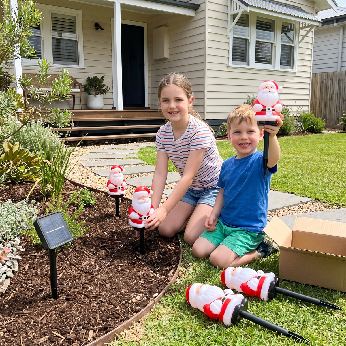 Children pushing Jolly solar Santa stake lights into a garden bed